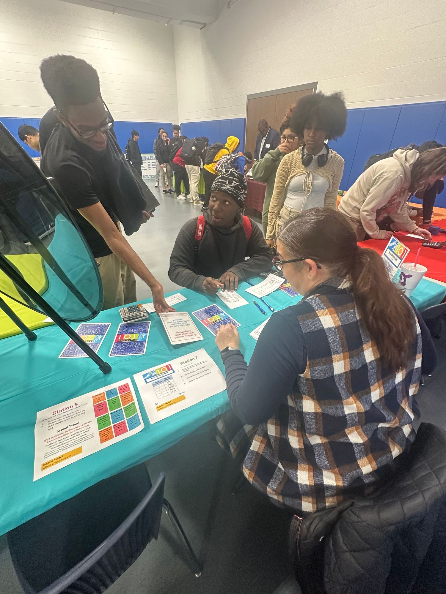 Students gather at informational tables during a school career fair event in a gymnasium.