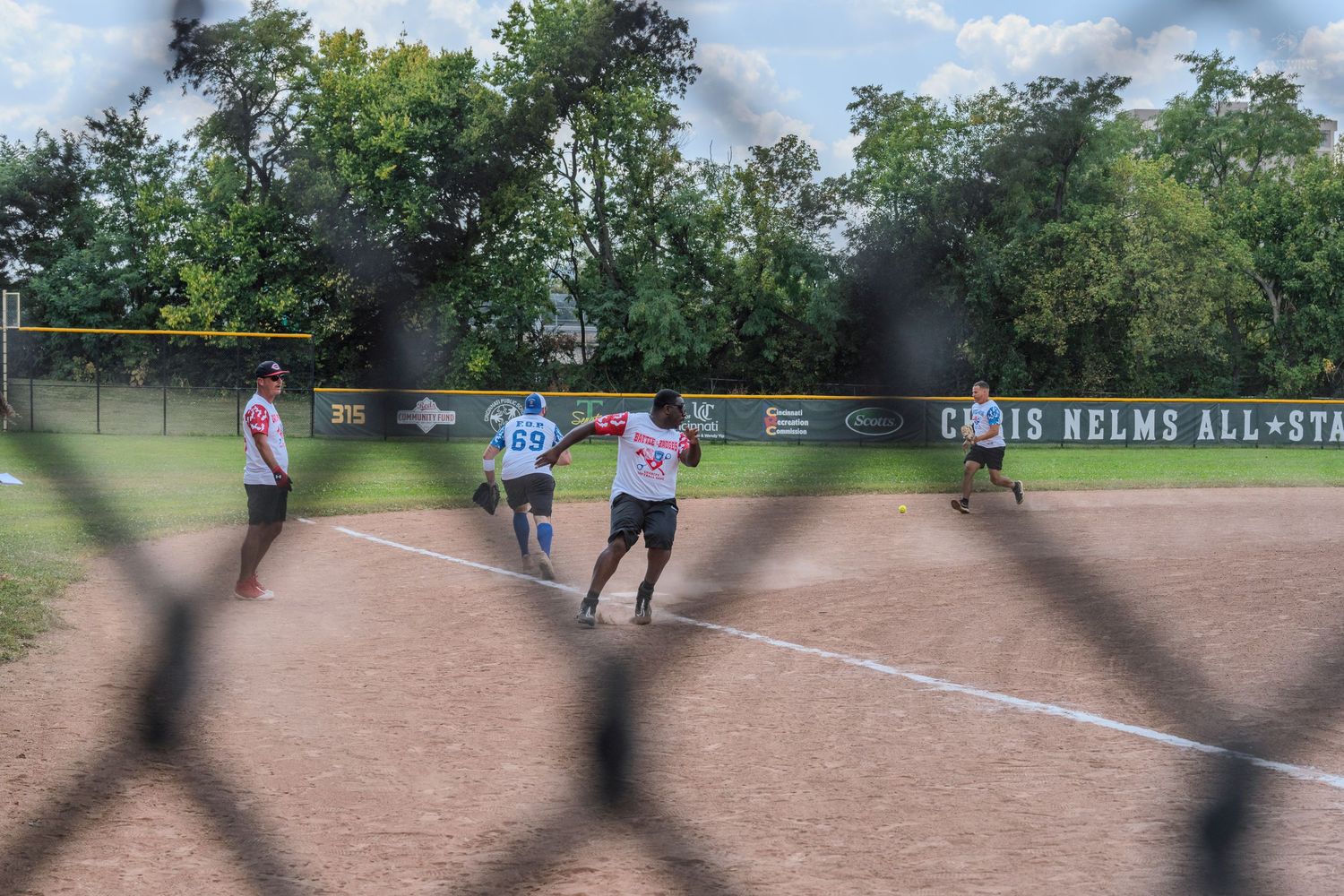 Players compete during the Chris Nelms All-Star softball game on a dirt field.
