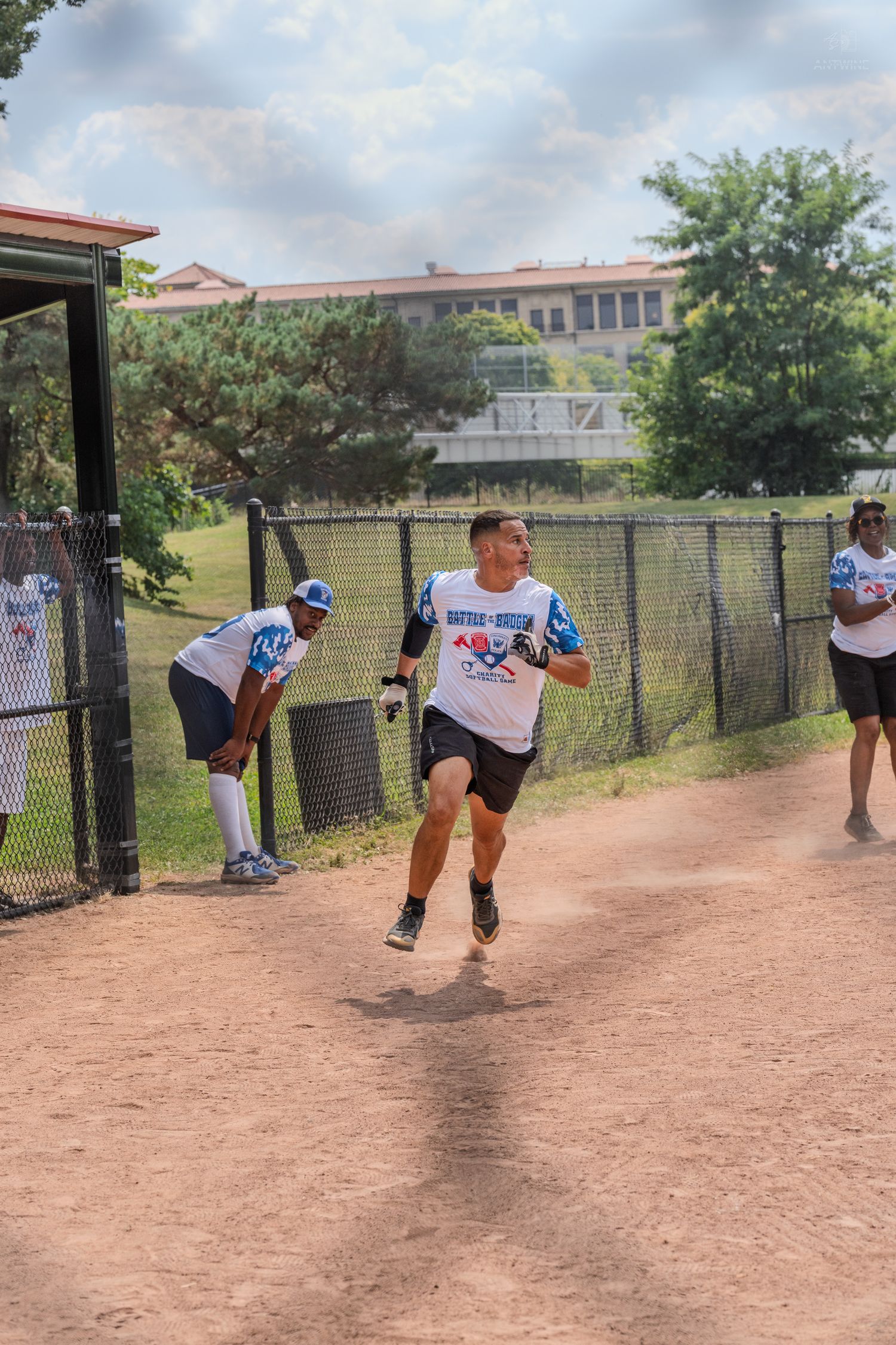 Male softball player in white uniform sprinting along the baseline during an outdoor recreational game.