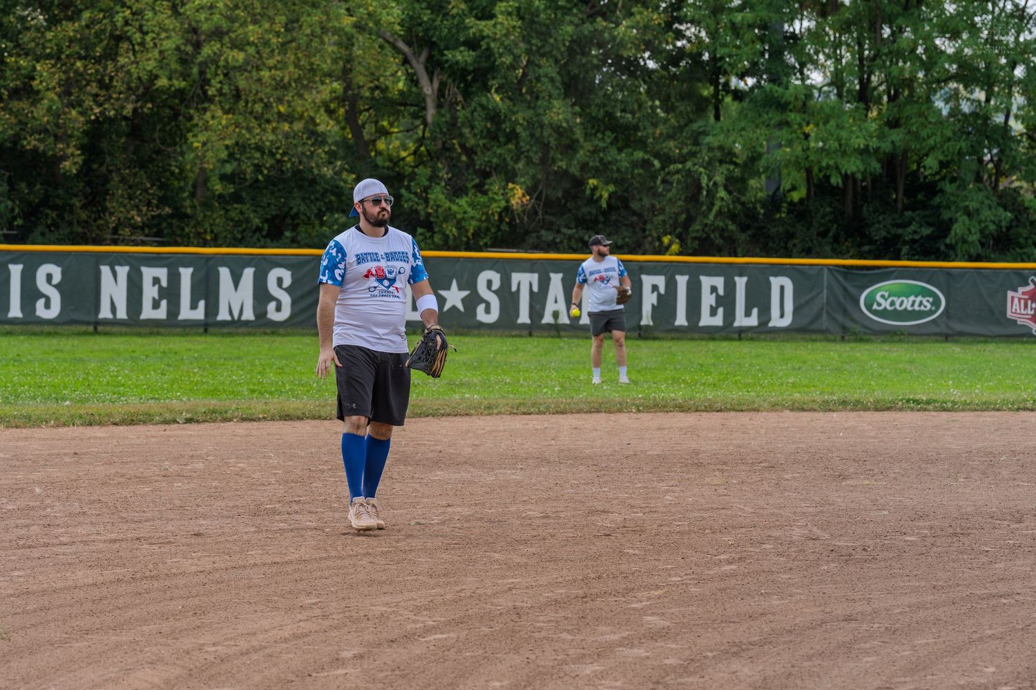 Baseball player walking across a dirt infield at Louis Nelms Stansfield outdoor ballpark.