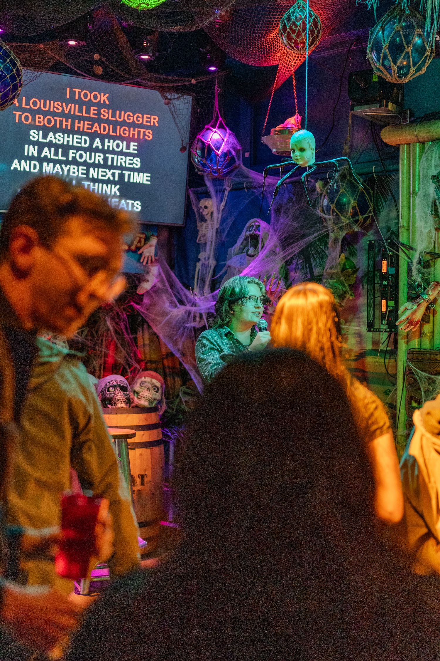 Crowd enjoying Halloween karaoke night at Hula Hula bar Seattle with spooky decorations.
