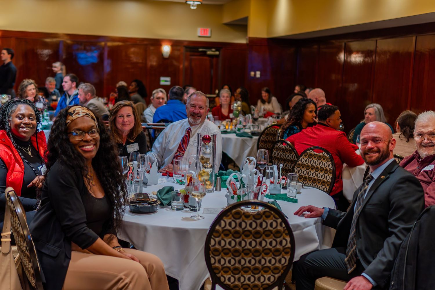 Diverse group of professionals smiling at a formal banquet dinner event in an elegant ballroom setting.