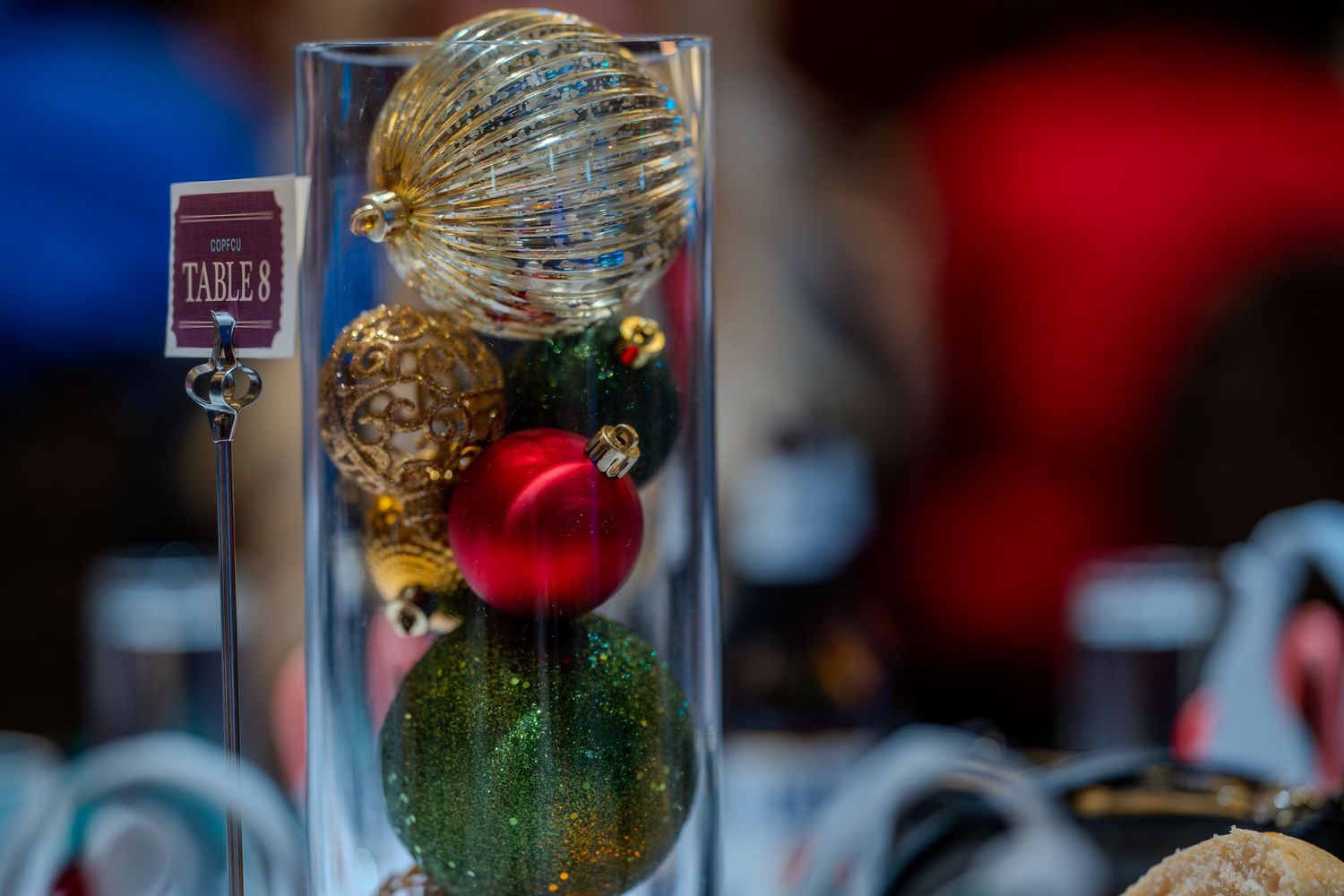 Colorful Christmas ornaments displayed in a clear glass cylinder vase as a festive holiday table centerpiece.