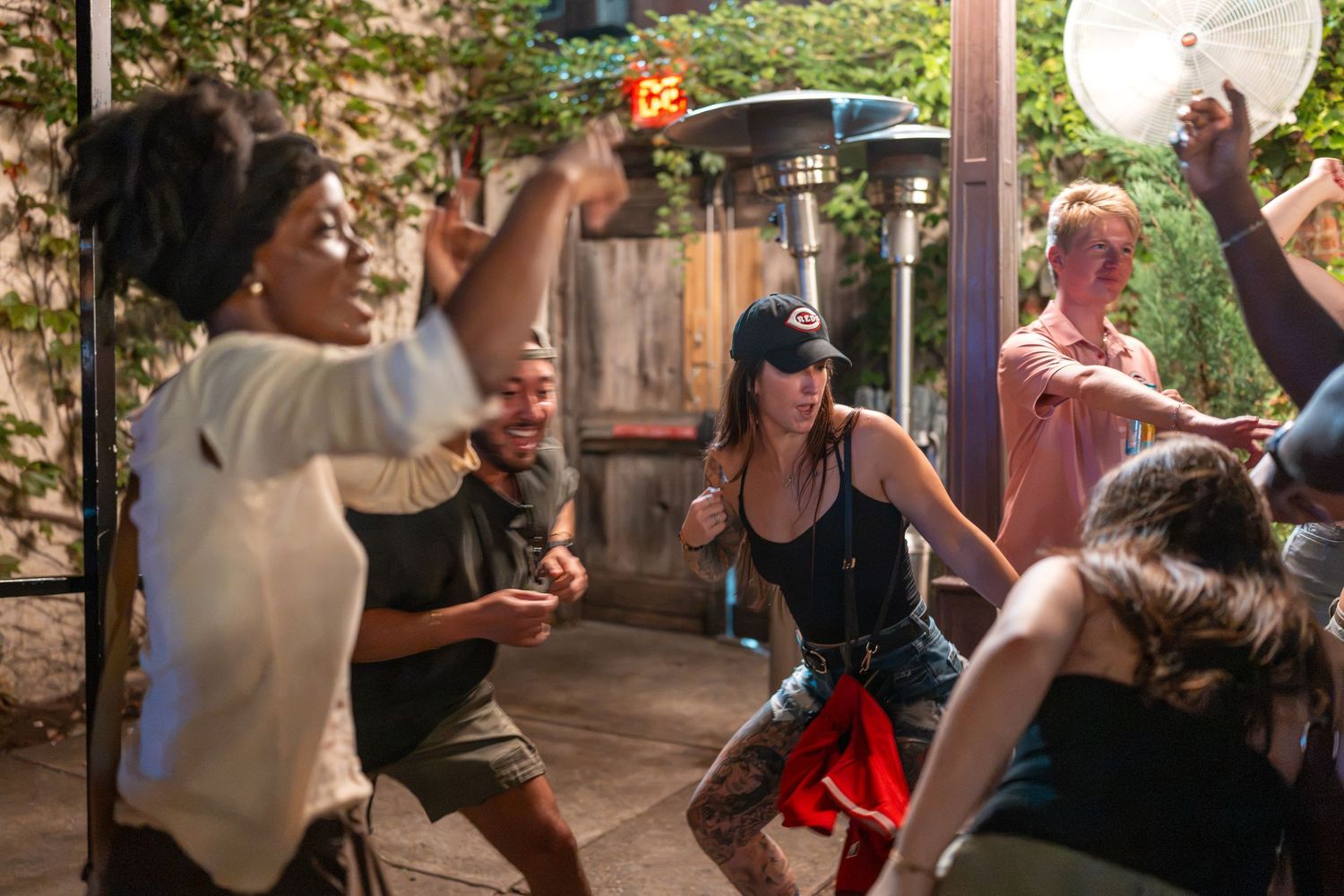 Group of friends dancing and having fun outdoors at a lively backyard party on a sunny day.