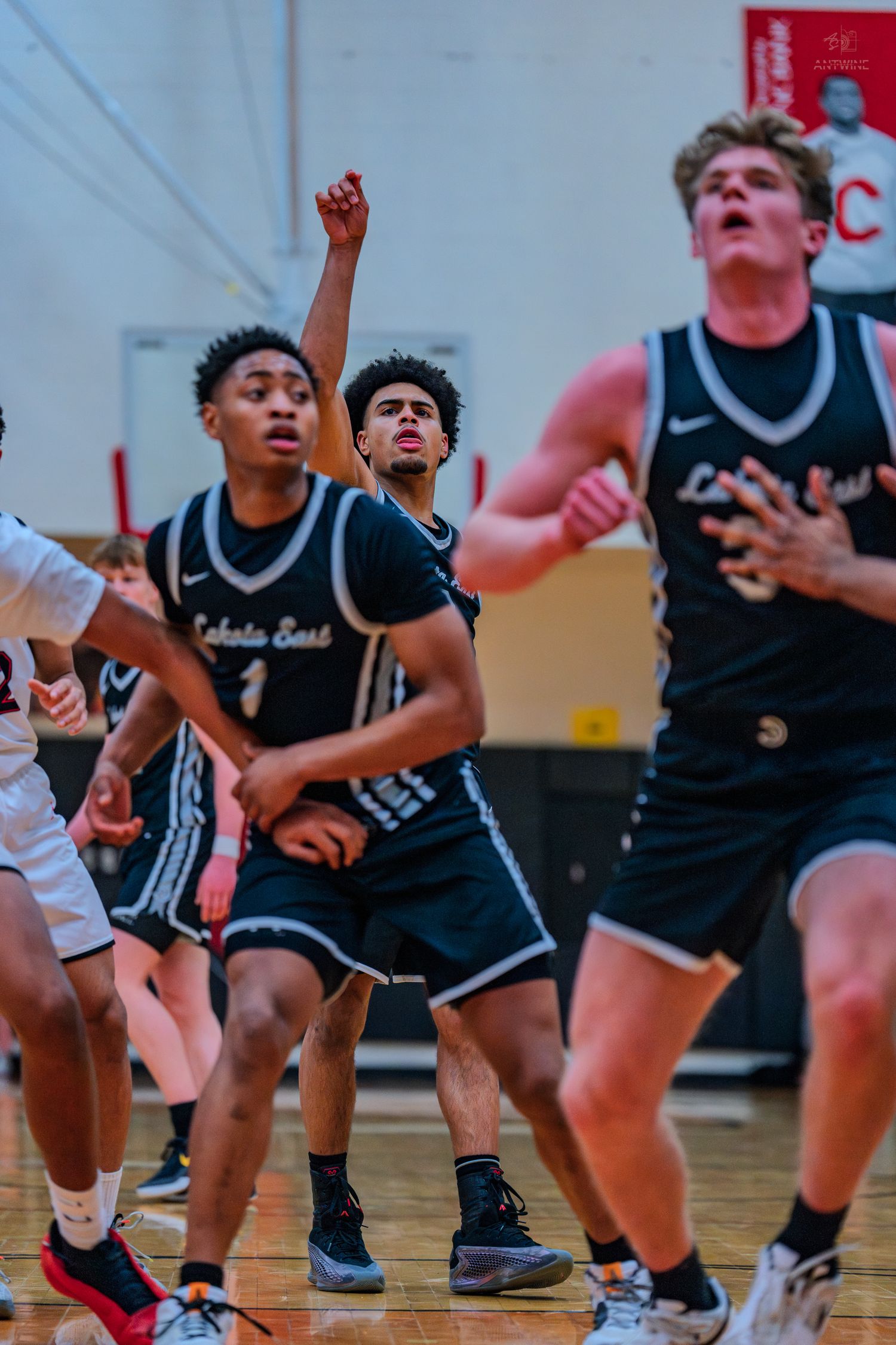 Lakota East basketball players box out during a high school game in a red and white gymnasium.