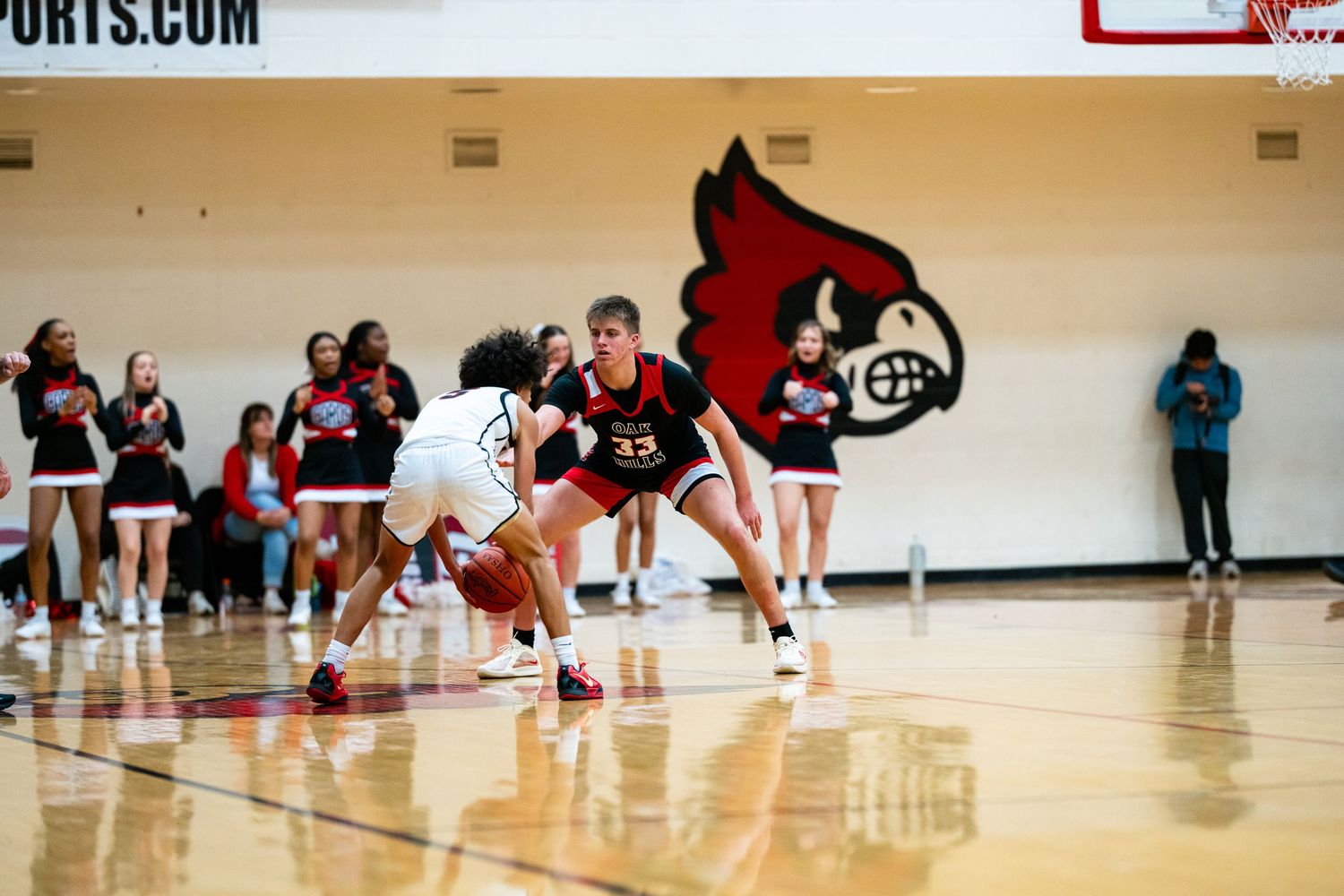 Player #33 in Cardinals uniform defends opponent dribbling during high school basketball game.