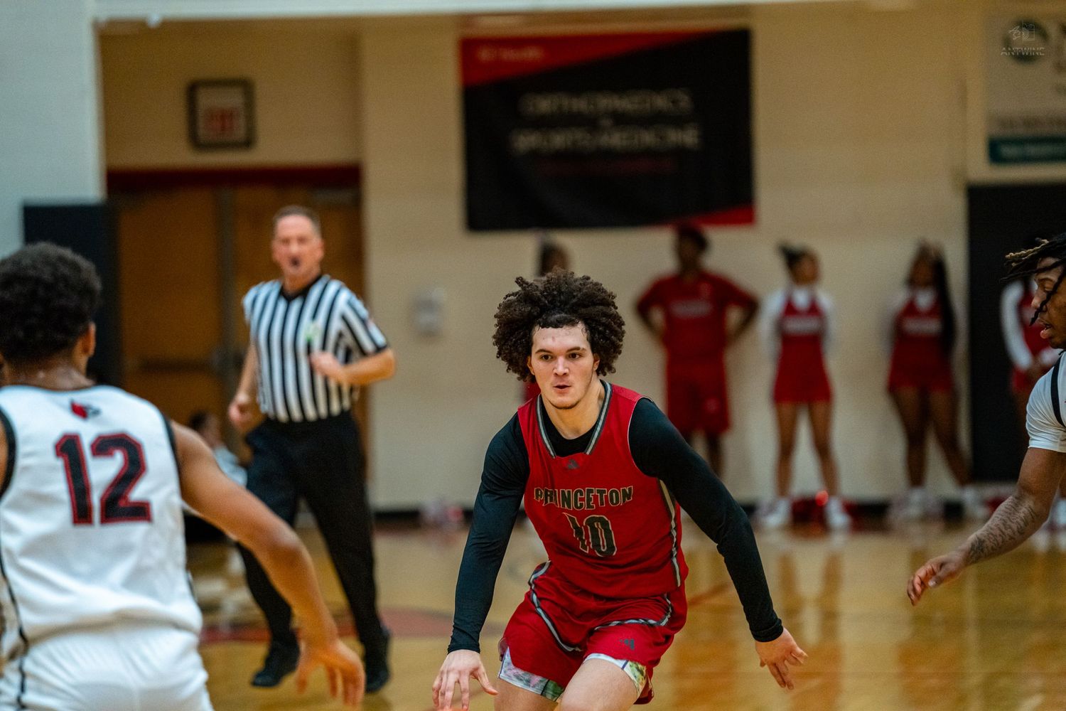 High school basketball player in red uniform dribbles down the court during an intense game.