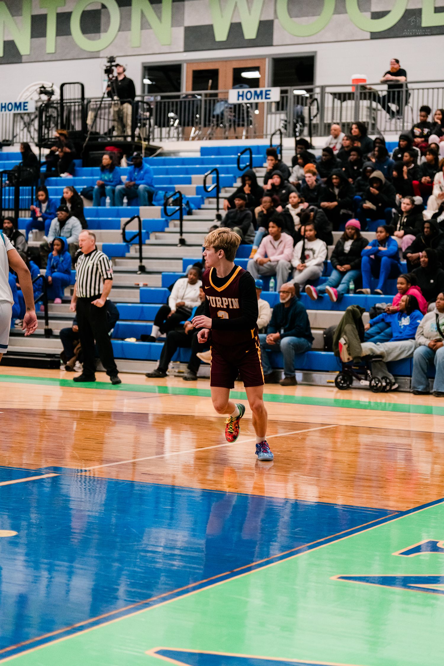 Turpin basketball player dribbles upcourt at Winton Woods arena with a packed crowd watching from the bleachers.
