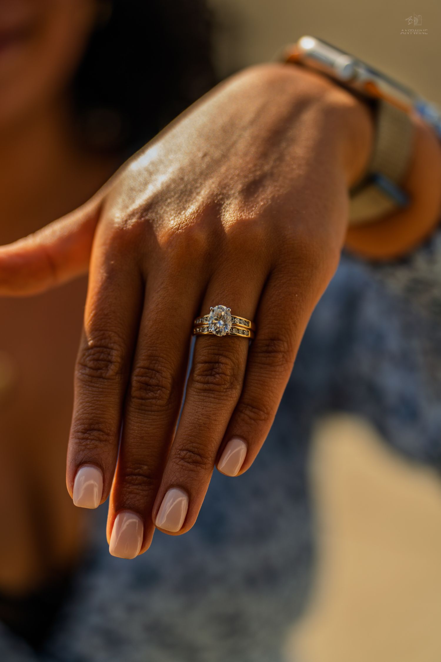 Close-up of a woman's hand displaying a stunning gold diamond engagement ring with elegant nail polish.