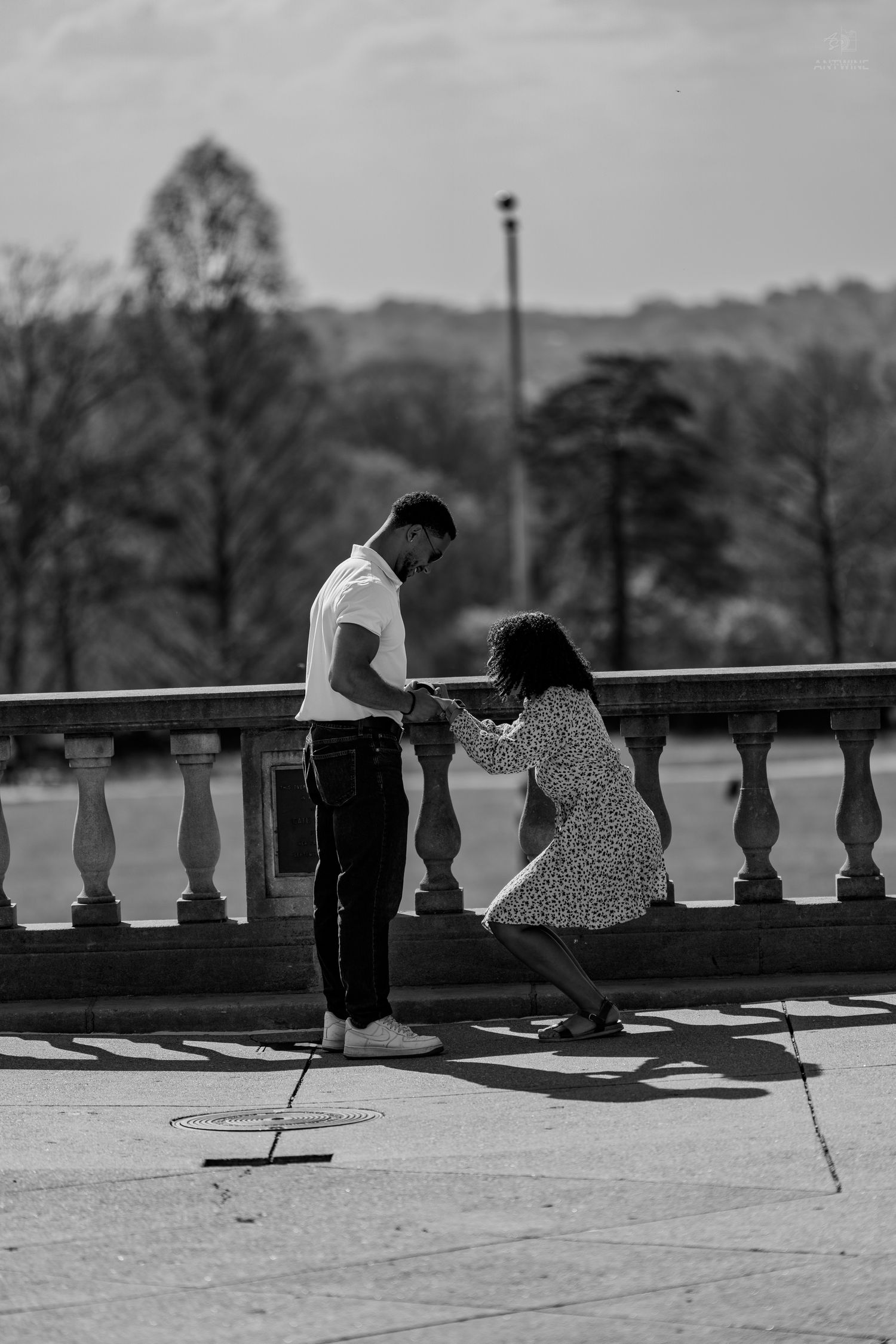 Black and white photo of a couple holding hands on a classic stone balustrade terrace.