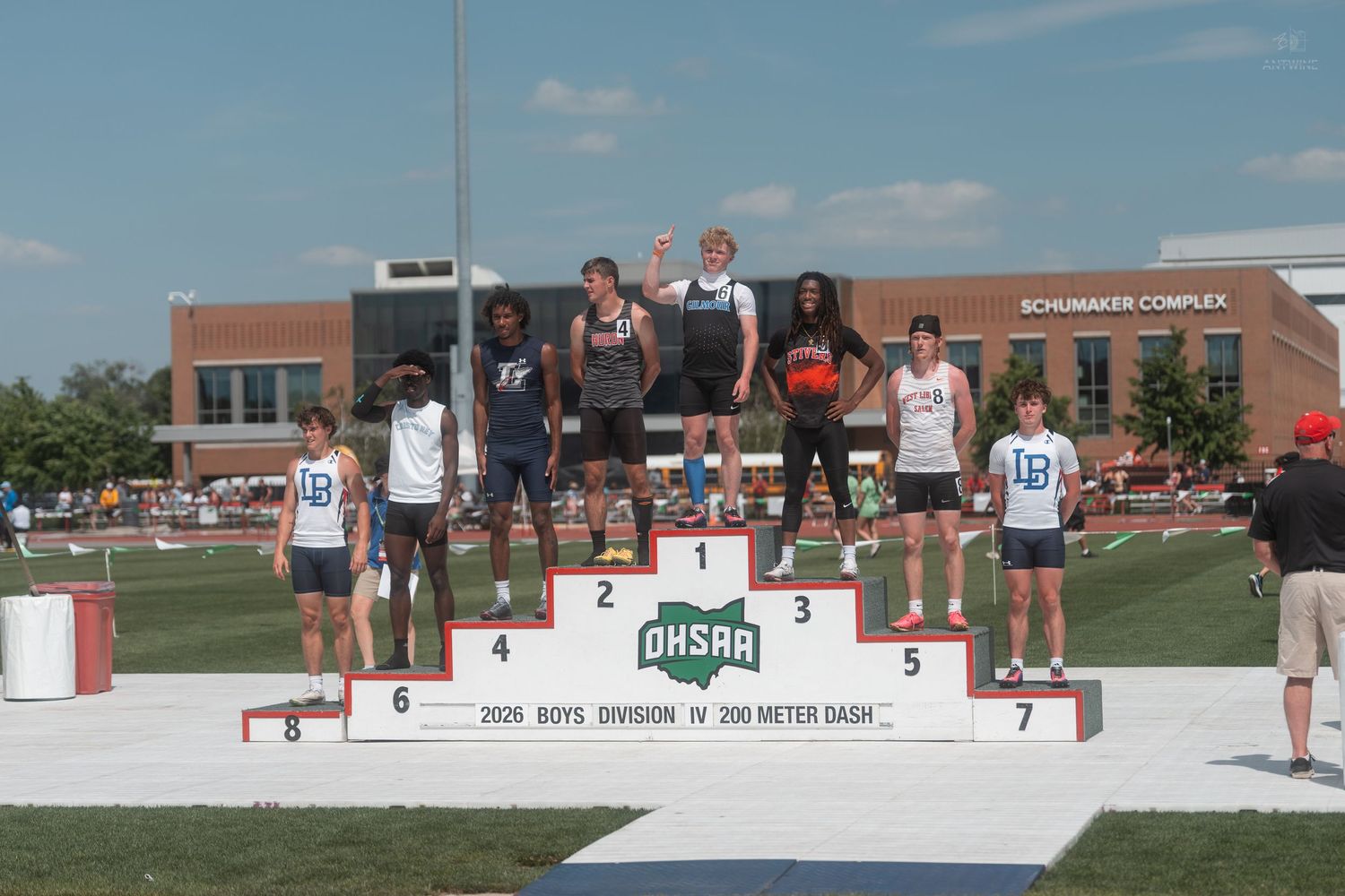 Athletes celebrate on the OHSAA Boys Division IV 200 Meter Dash awards podium at an outdoor stadium.
