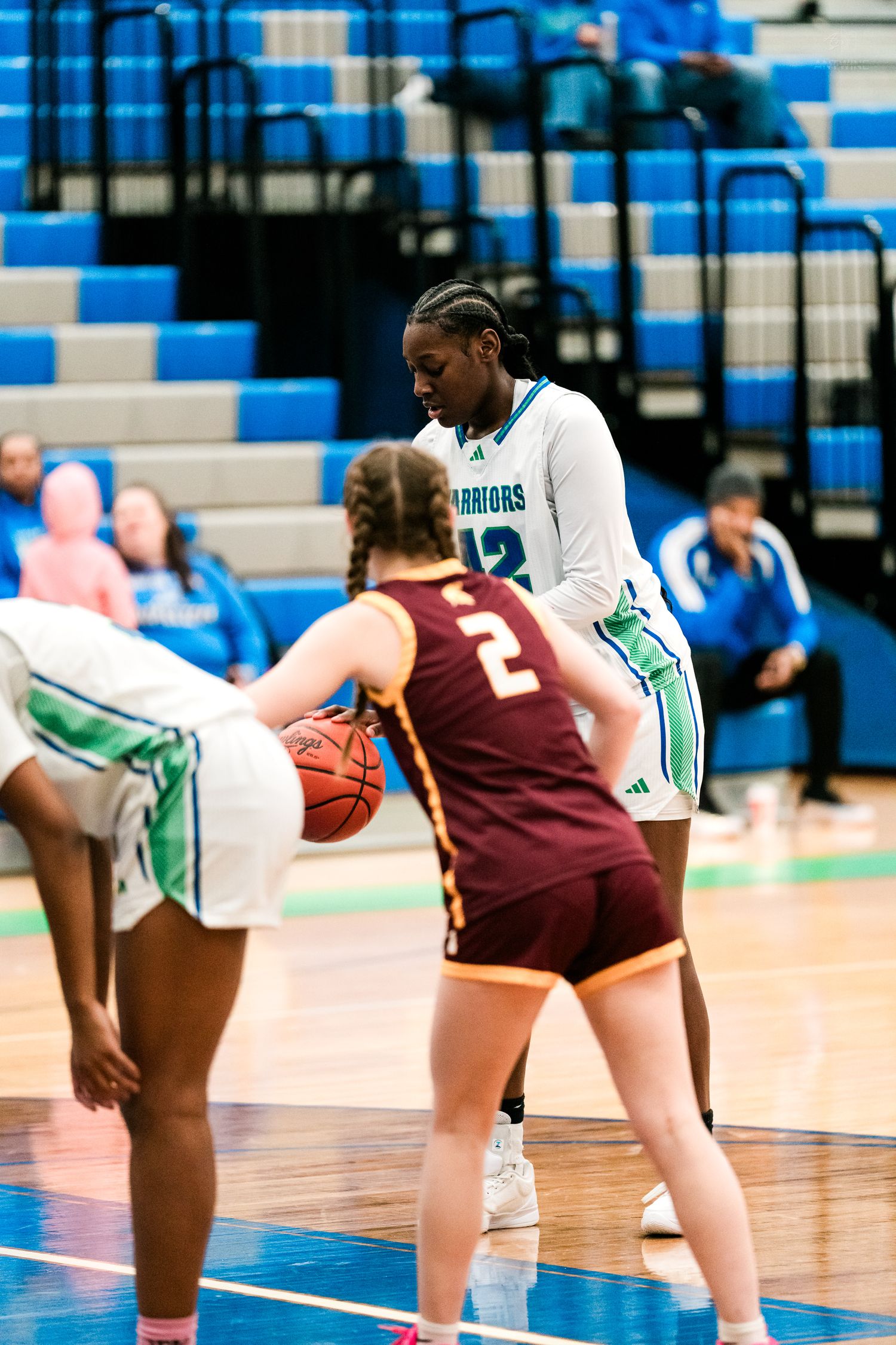 A tall Warriors player number 12 defends against Turpin player number 2 during a girls basketball game.