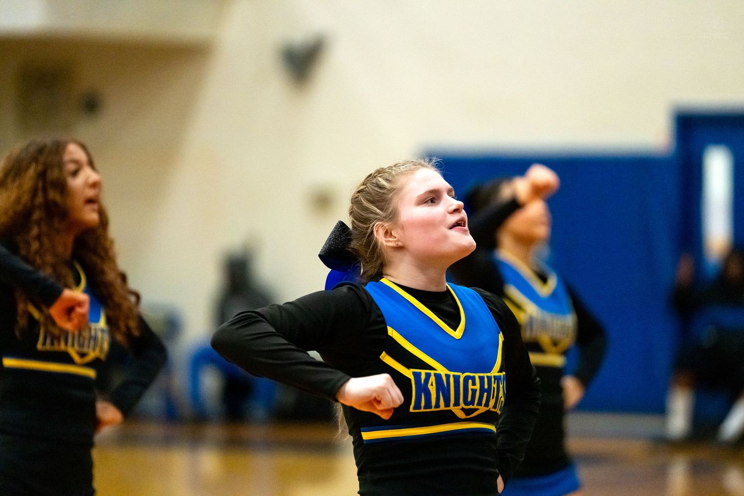 Knights cheerleader in blue and gold uniform performs energetic routine during basketball game.