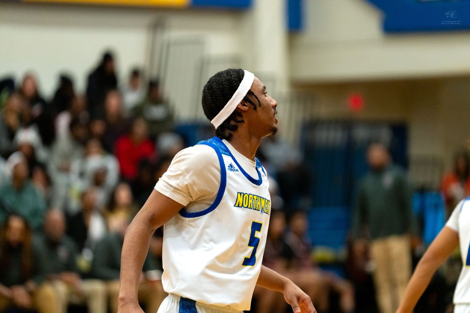 High school basketball player number 5 in white uniform looks up during an indoor basketball game.
