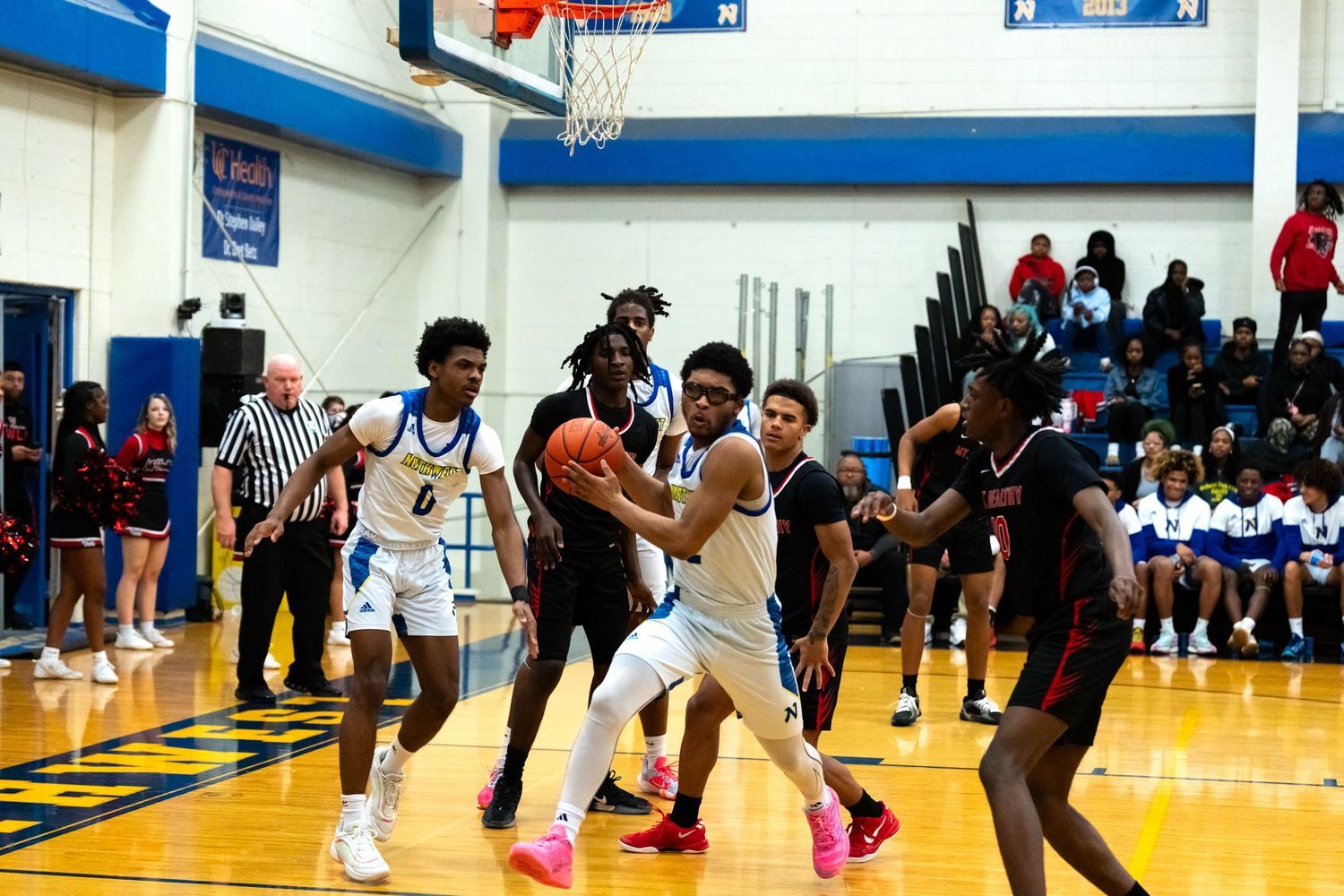High school basketball player drives to the basket during a competitive game in a packed gymnasium.
