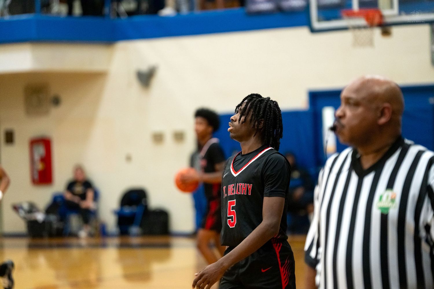 Player wearing number 5 red jersey stands at free throw line with referee nearby.