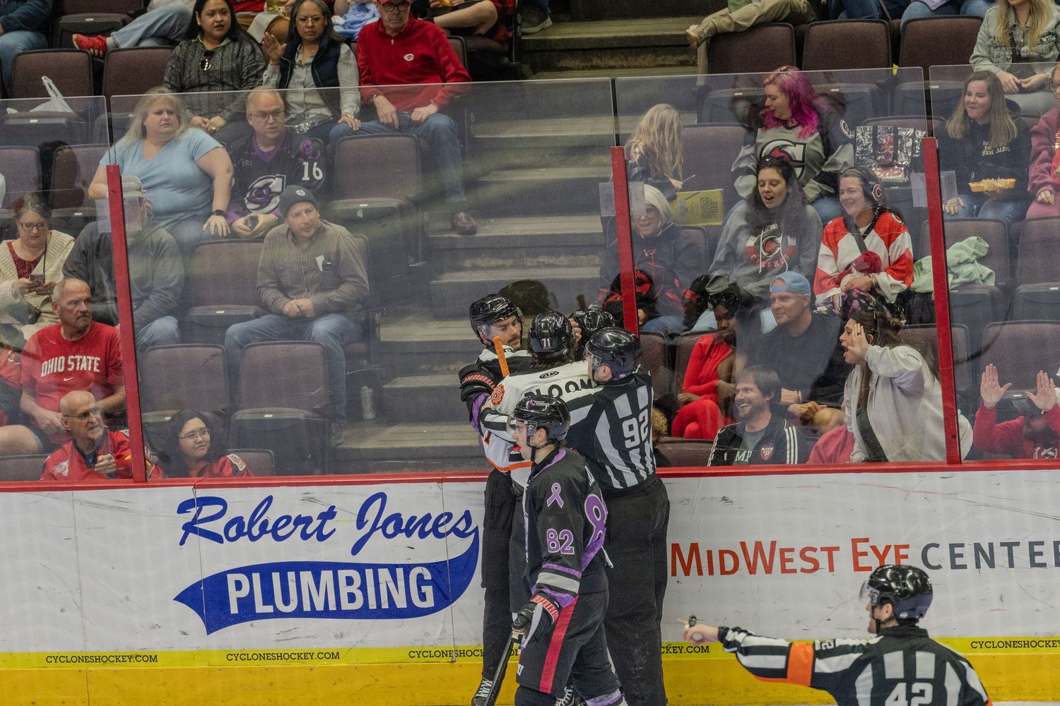 Hockey referee separates two players during an intense altercation on the ice rink during a professional hockey game.