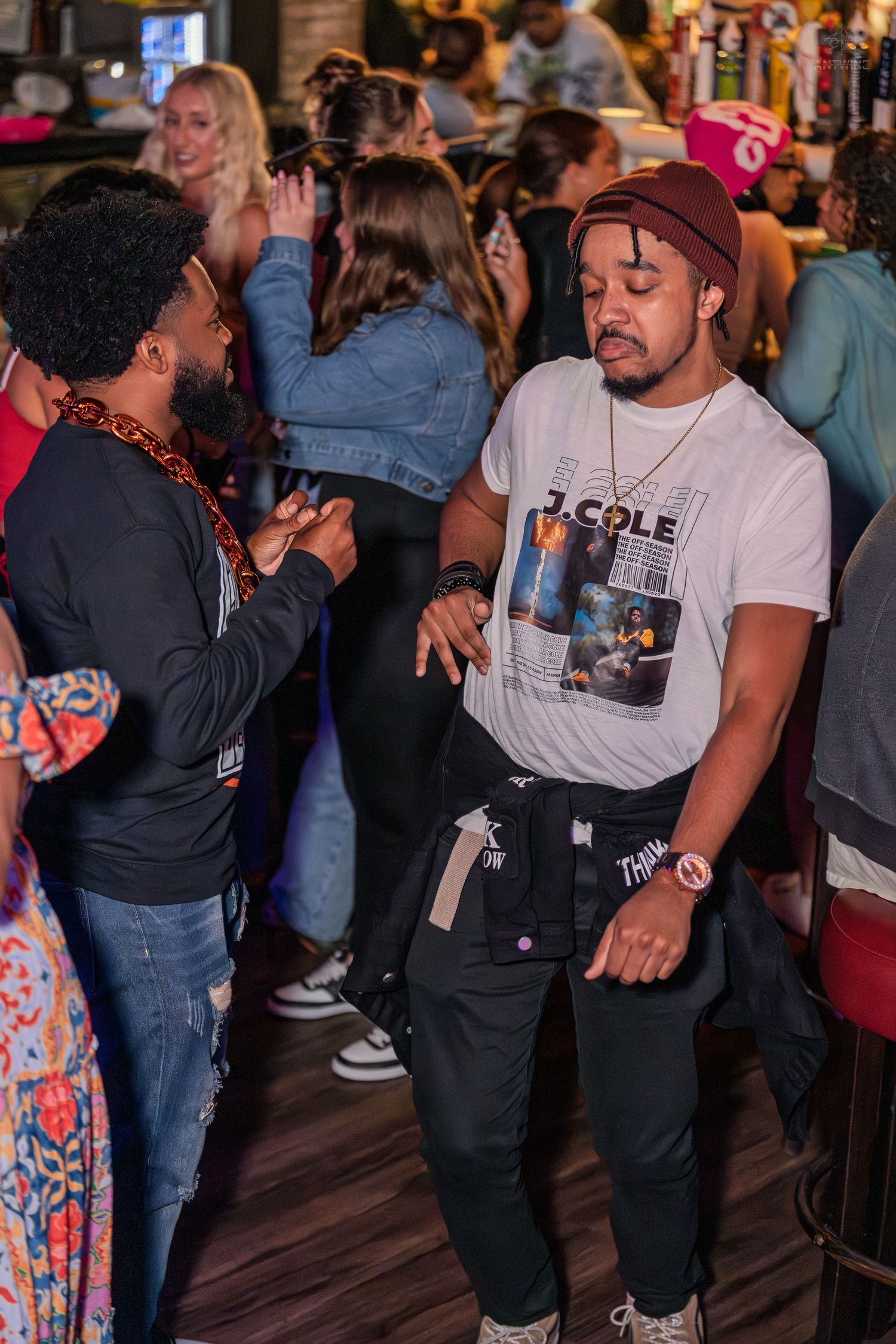 Two men socializing and dancing at a crowded bar nightlife event.