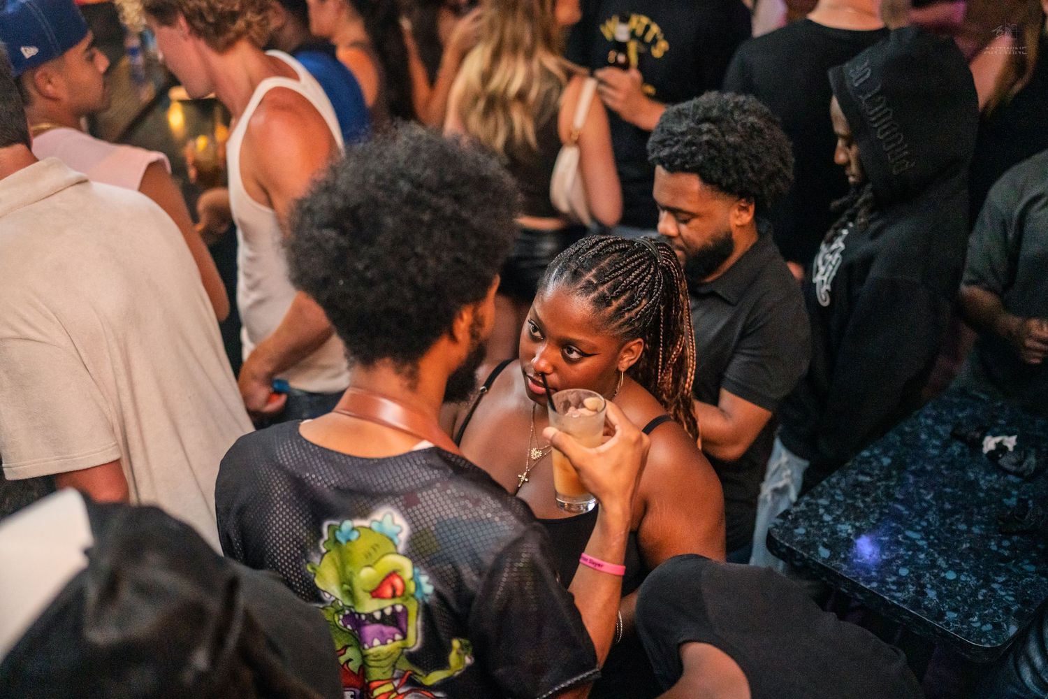 Young couple sharing an intimate moment on a crowded dance floor at a nightclub party.