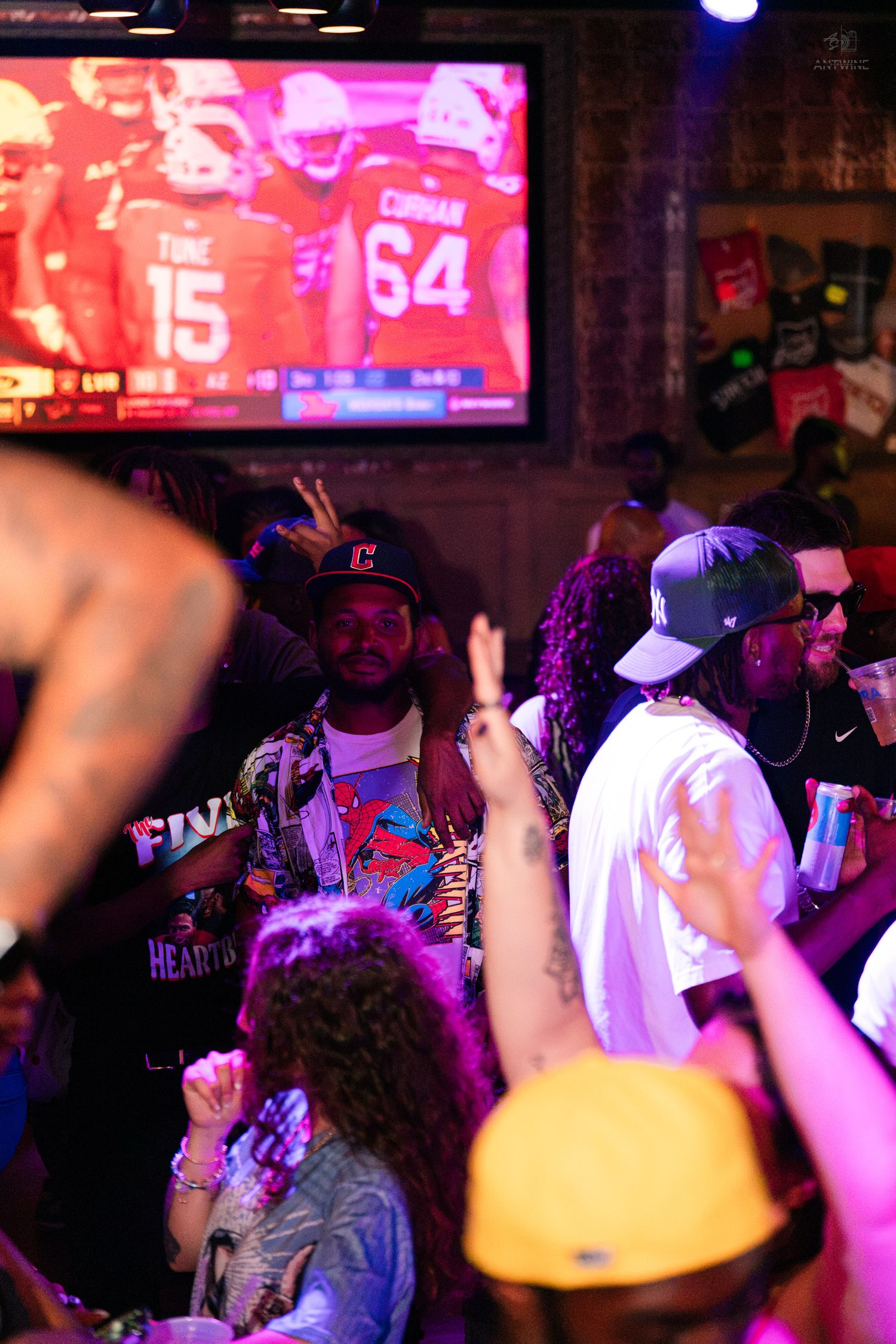 Energetic crowd dancing under purple lights at a sports bar party.