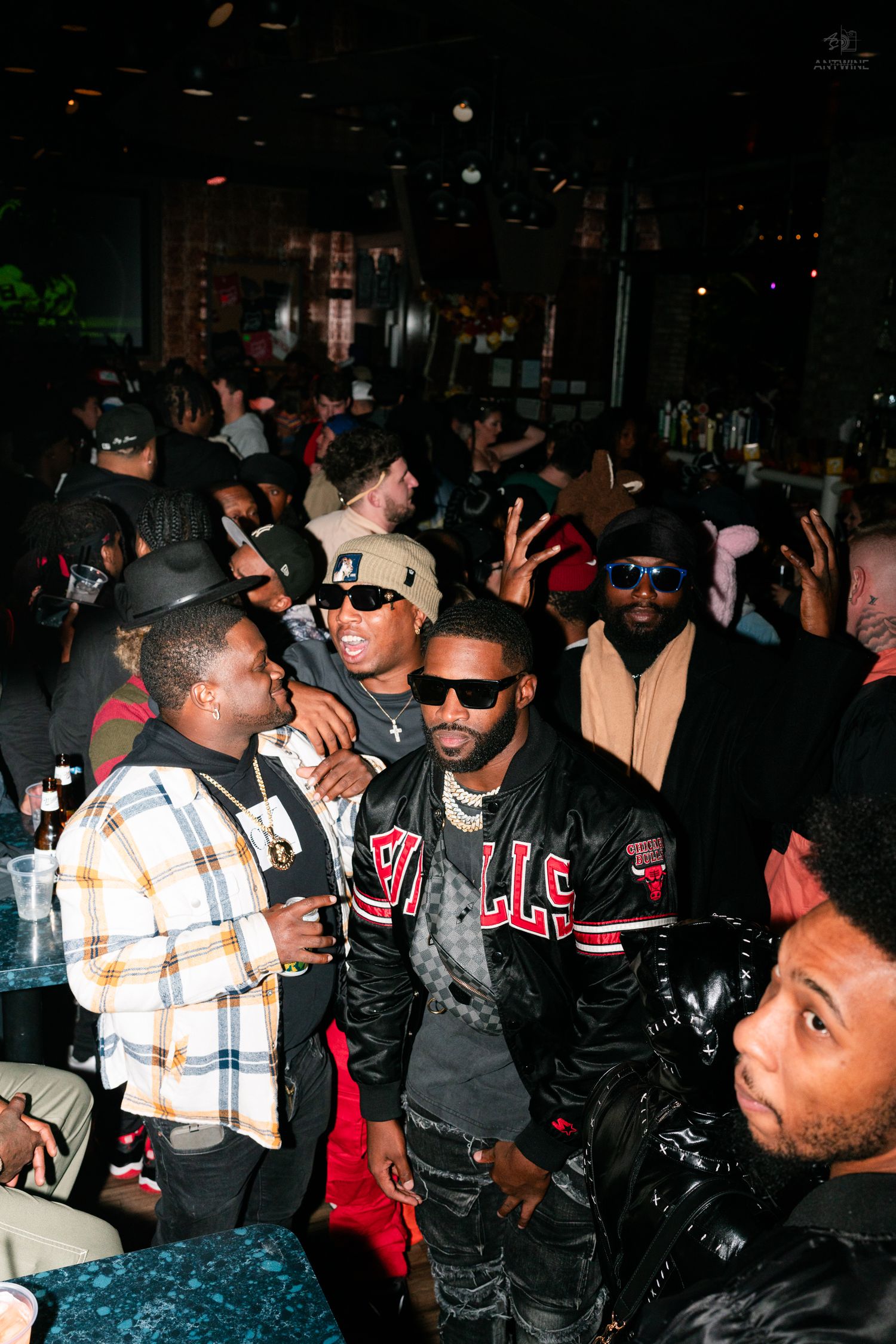 Men in casual streetwear posing at a lively nightclub gathering.