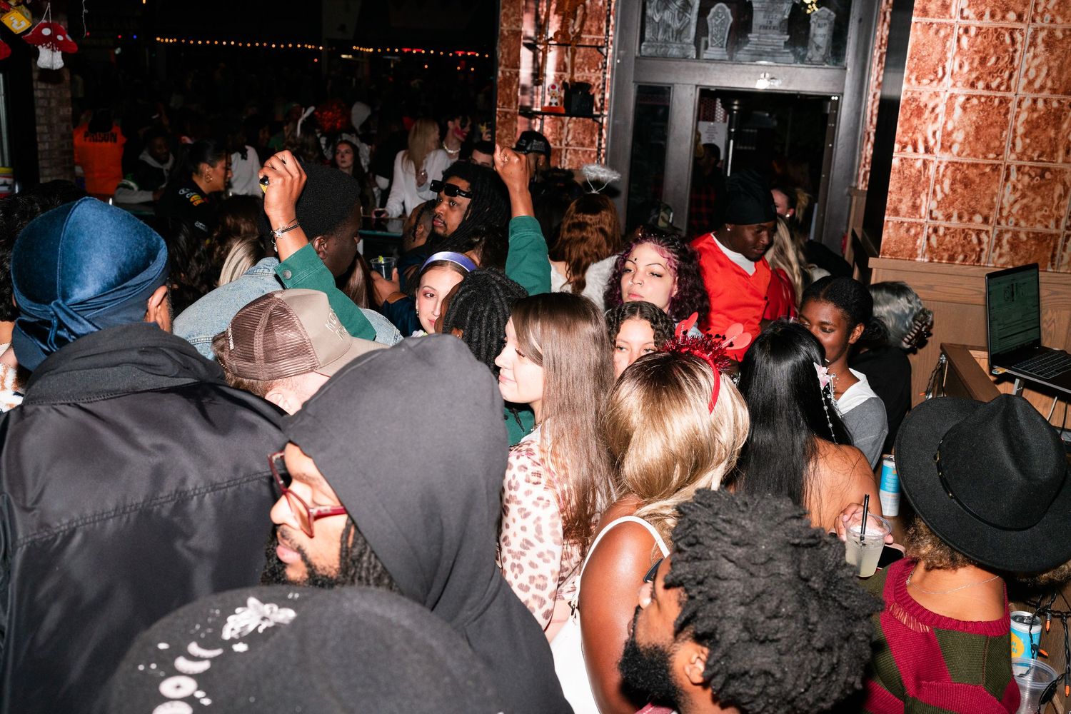 Large crowd of partygoers packed together at a lively indoor Halloween event.