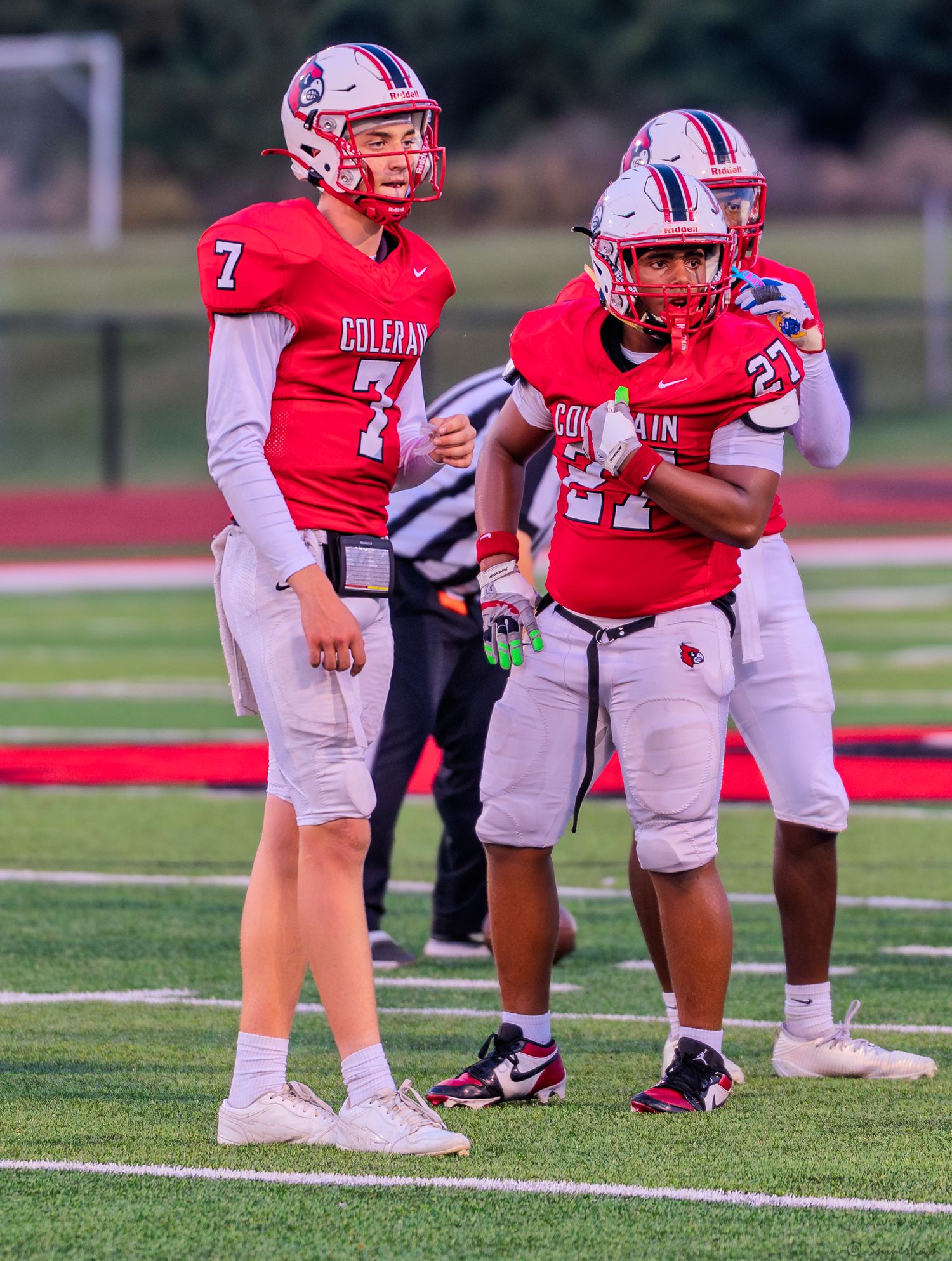 Two Colerain football players wearing red jerseys numbered 7 and 22 stand on the field during a game.