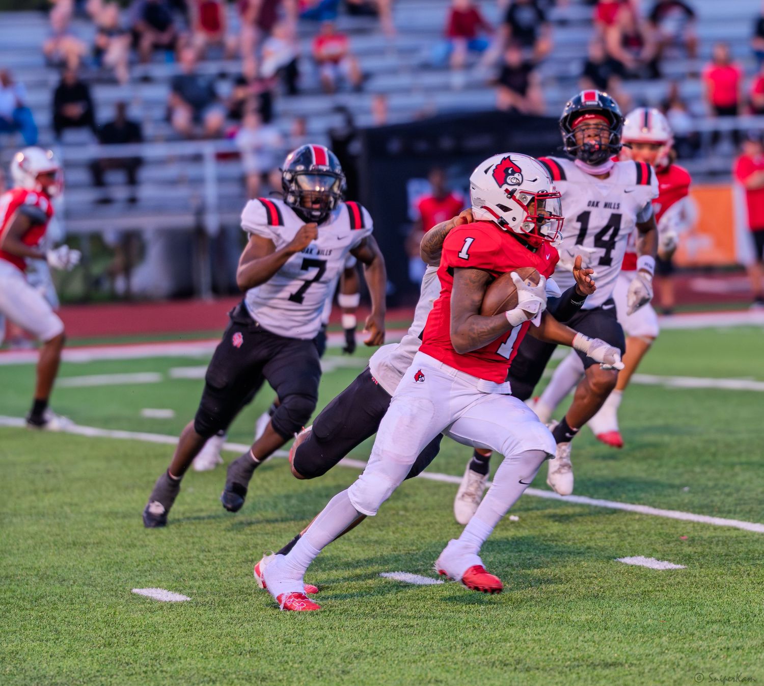 Colerain player #1 runs the ball as teammates #7 and #14 follow during a football game.
