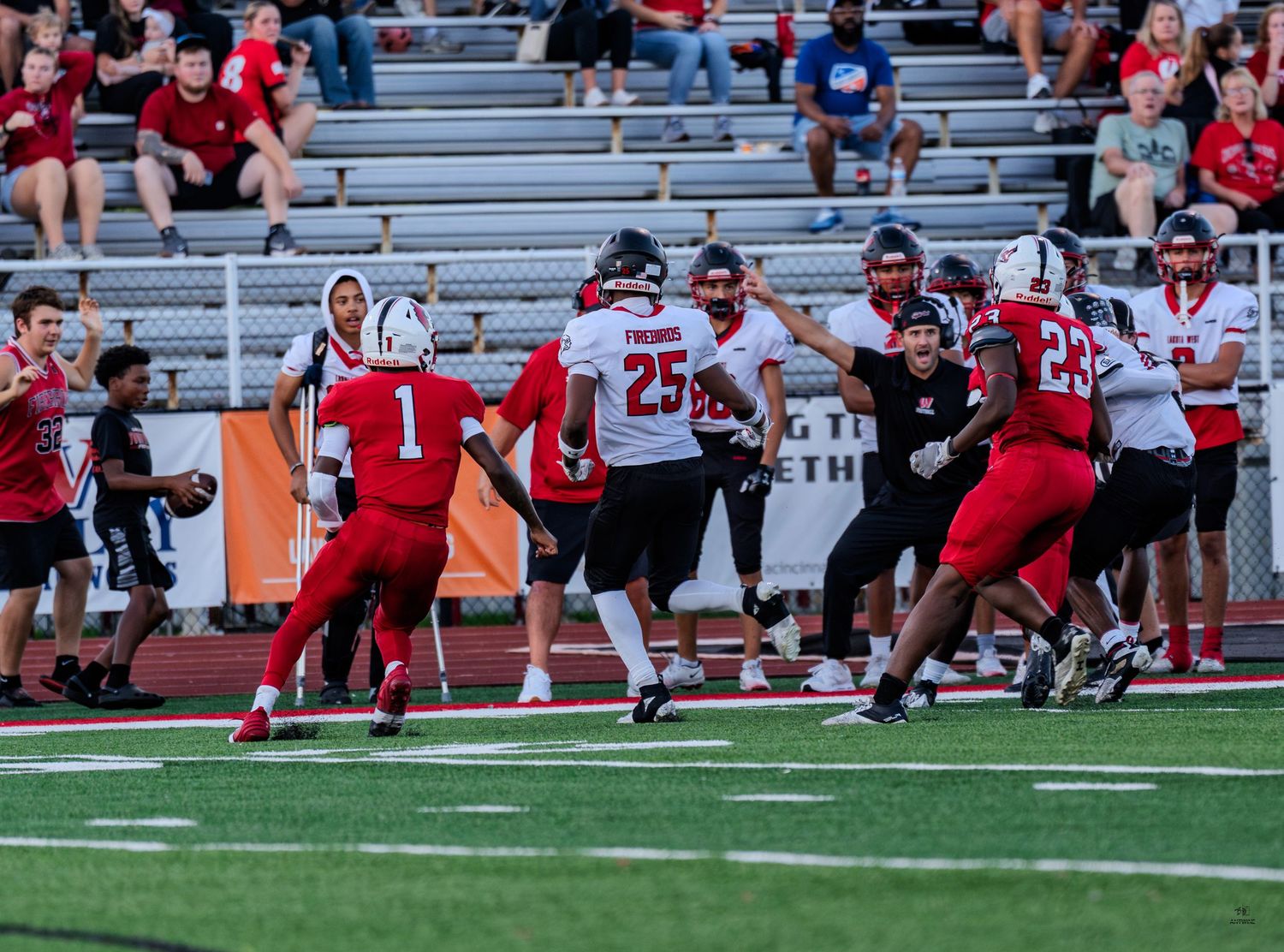Football player number 1 in red uniform prepares to make a play against white-uniformed defenders on the field.