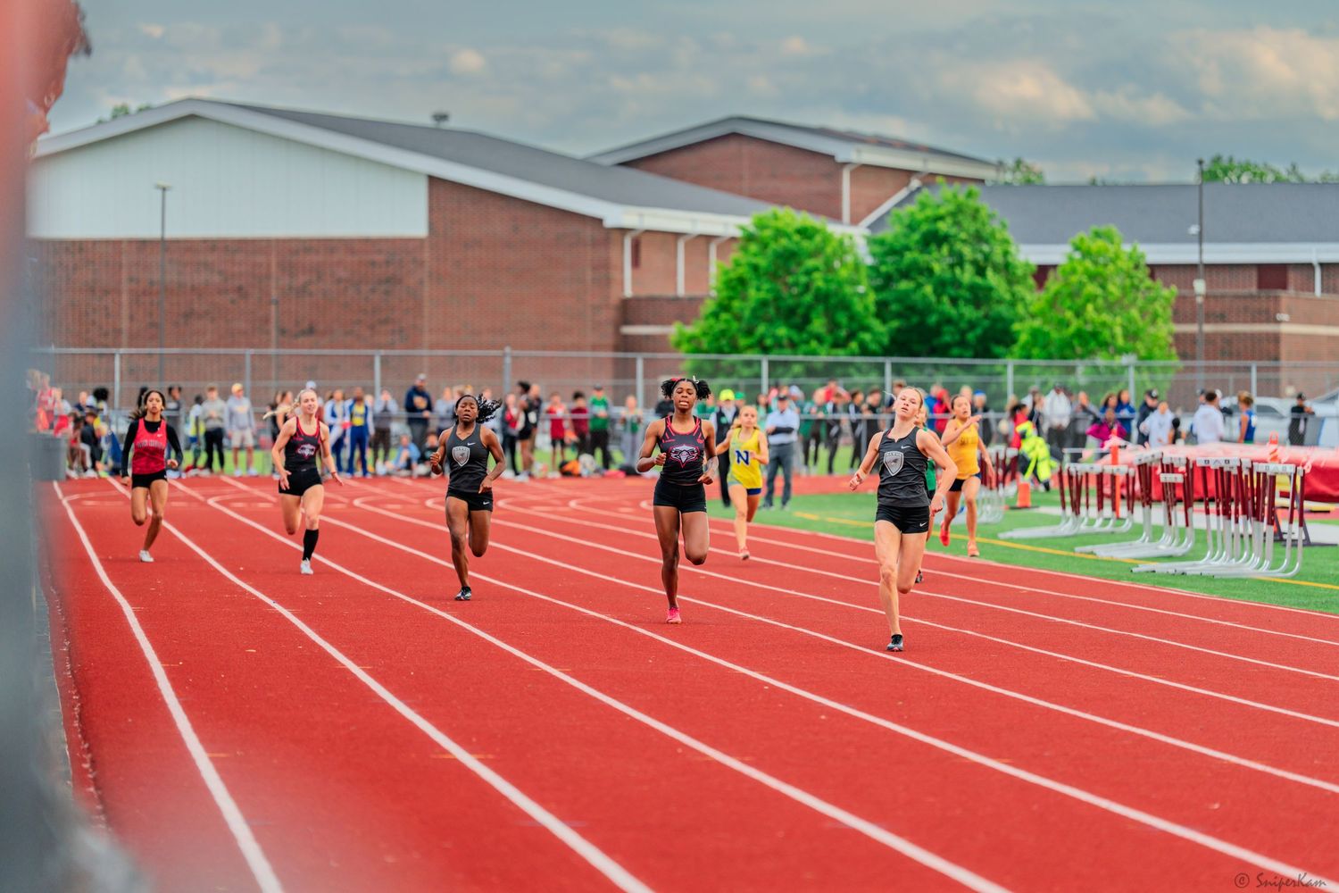 Female sprinters compete in a track race at Ross Rams stadium.