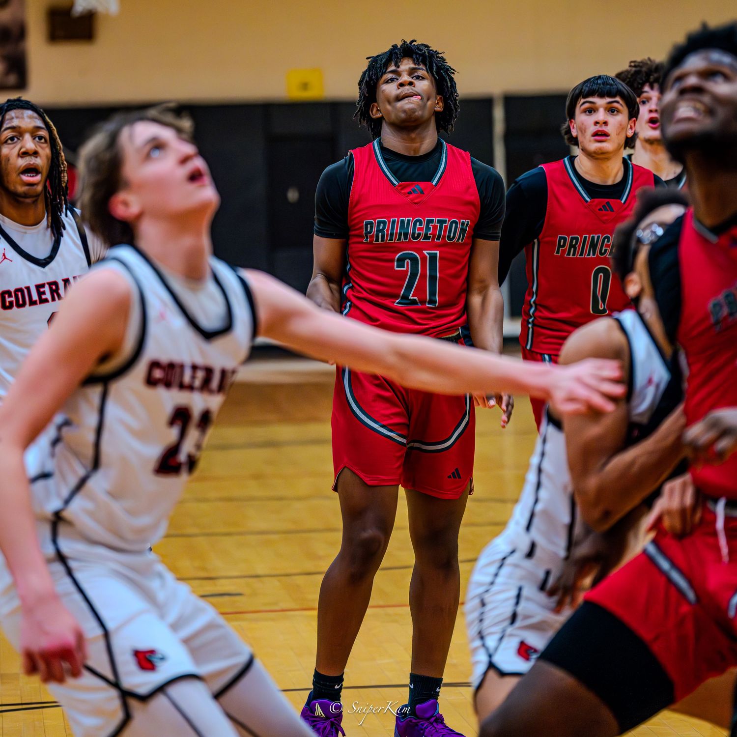 Princeton basketball players in red jerseys compete against Colerain during intense high school game.