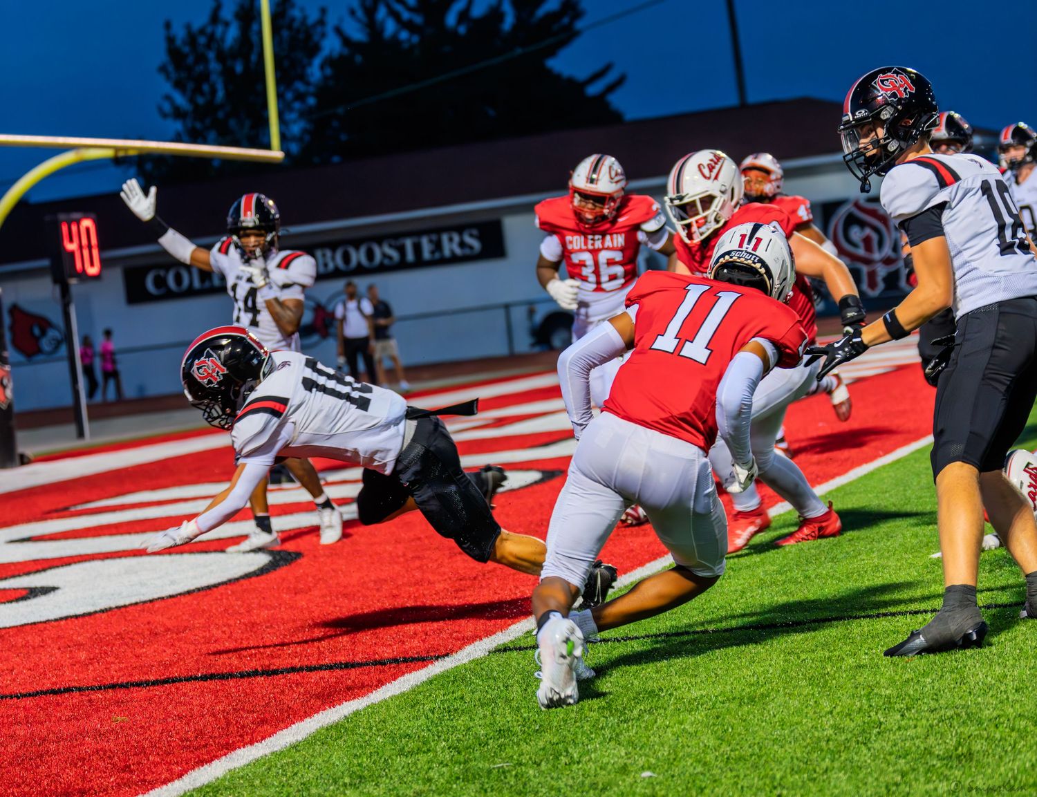 High school football player dives into the end zone attempting a touchdown during a Friday night game.