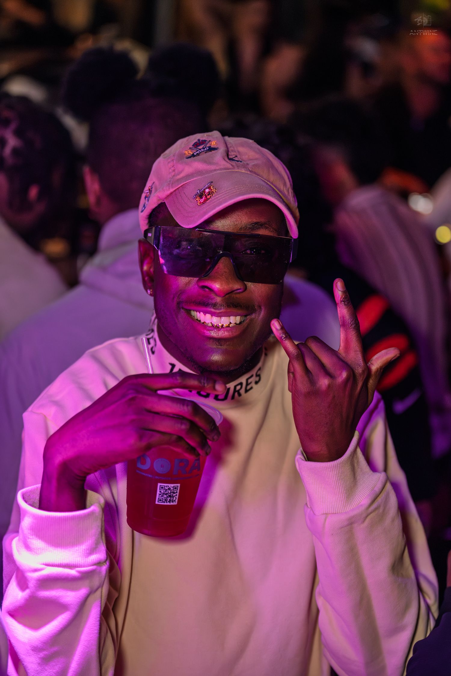 Smiling man in pink cap and sunglasses posing at nightclub party.