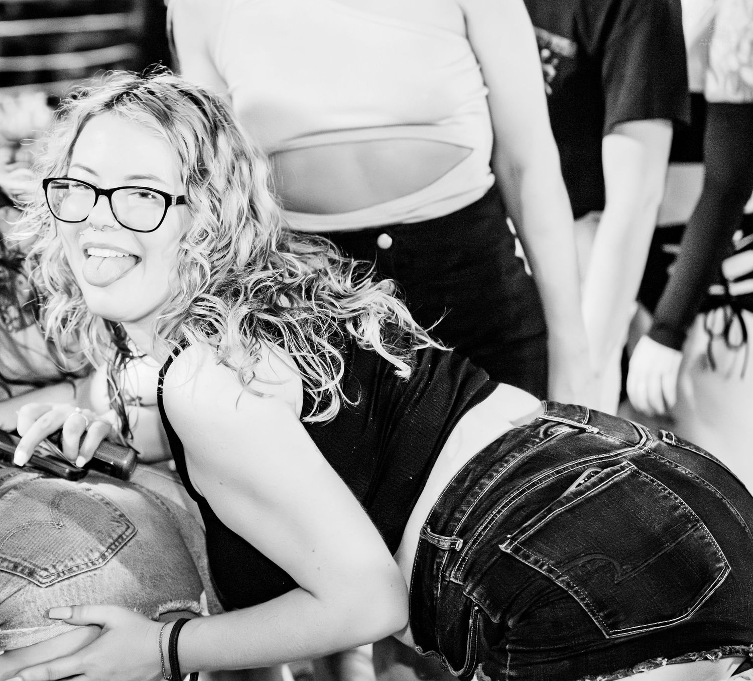Young woman with curly hair and glasses laughing at a casual outdoor event.
