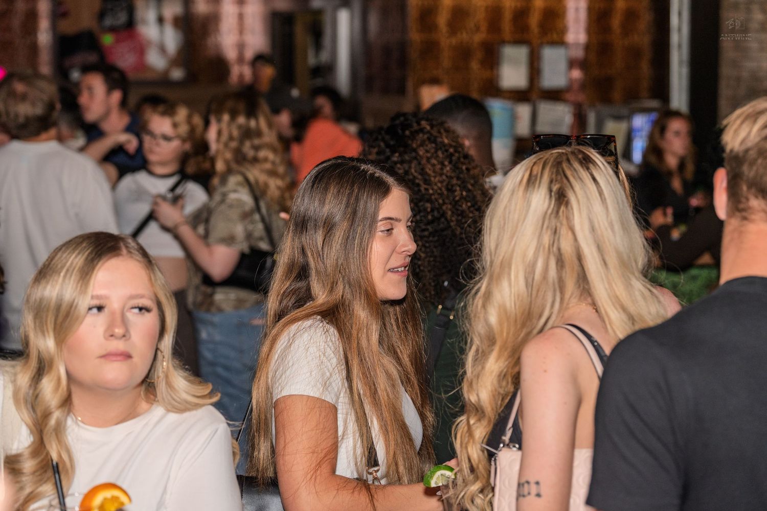 Group of young women socializing at a crowded indoor nightlife event.