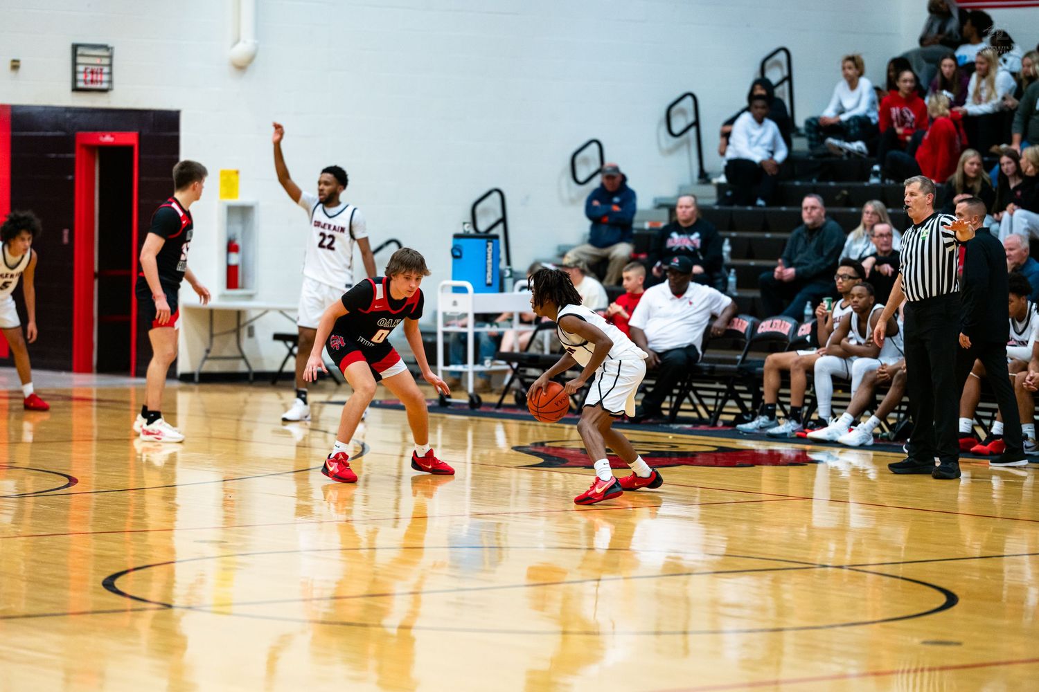 A basketball player in red dribbles upcourt with intensity during a high school basketball game.