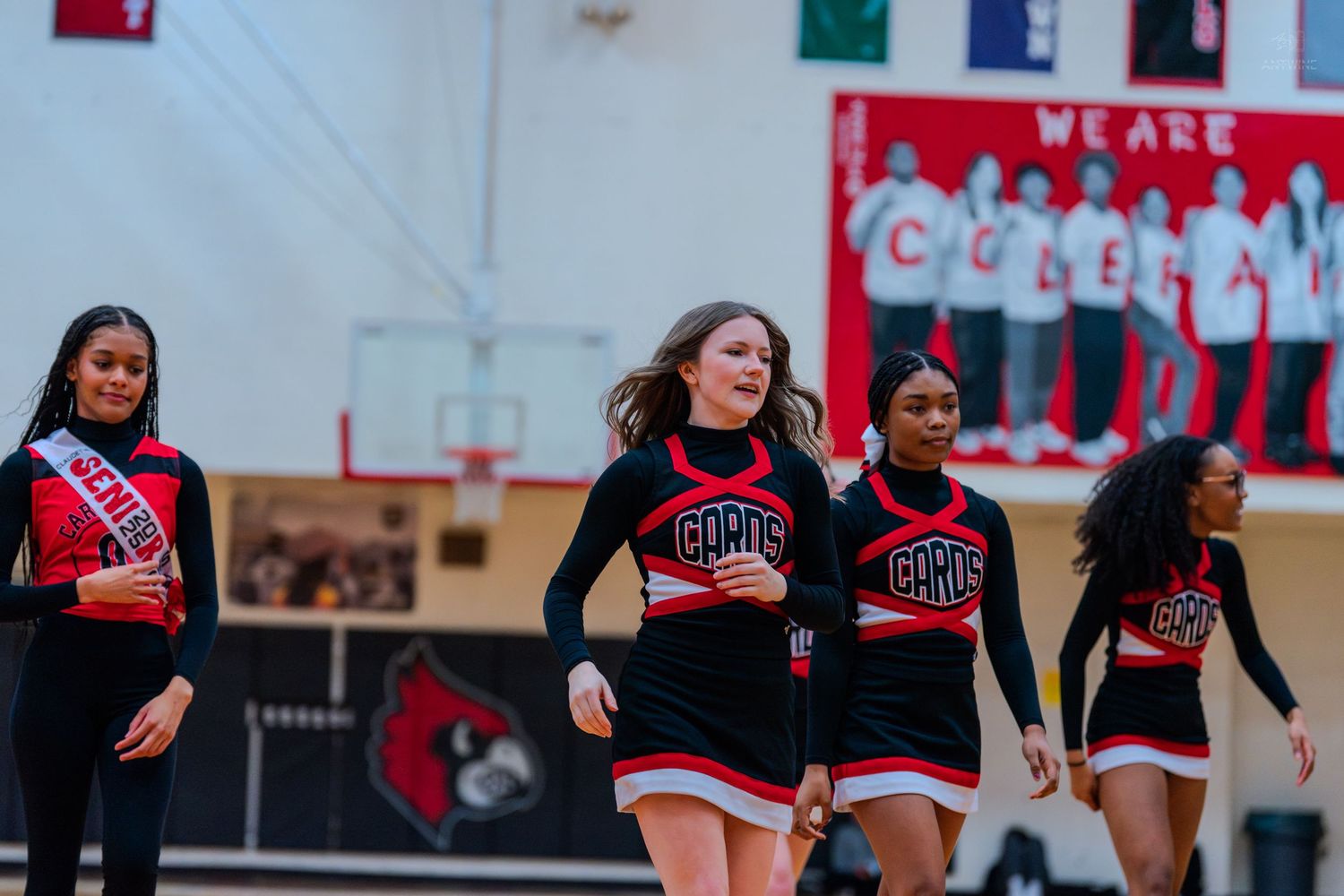 Coleman Middle School cheerleaders in red and black uniforms perform a routine under a We Are Coleman banner.