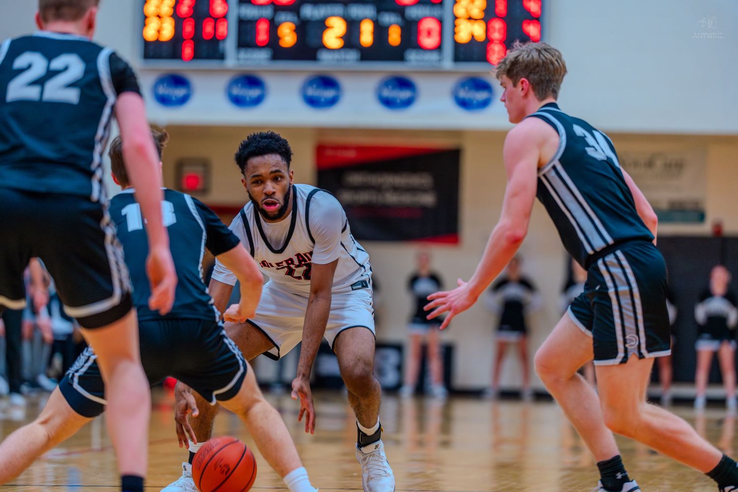 Colerain player drives through two defenders during a competitive high school basketball game.