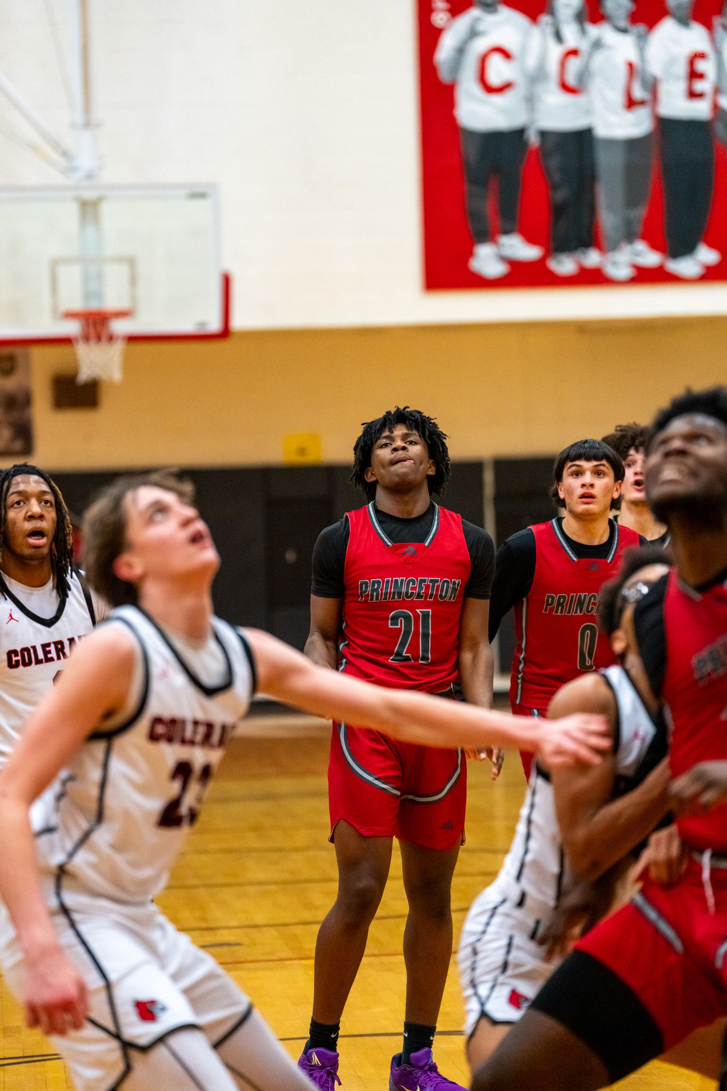 Princeton #21 and Coleman players battle for rebound position during competitive high school basketball game.