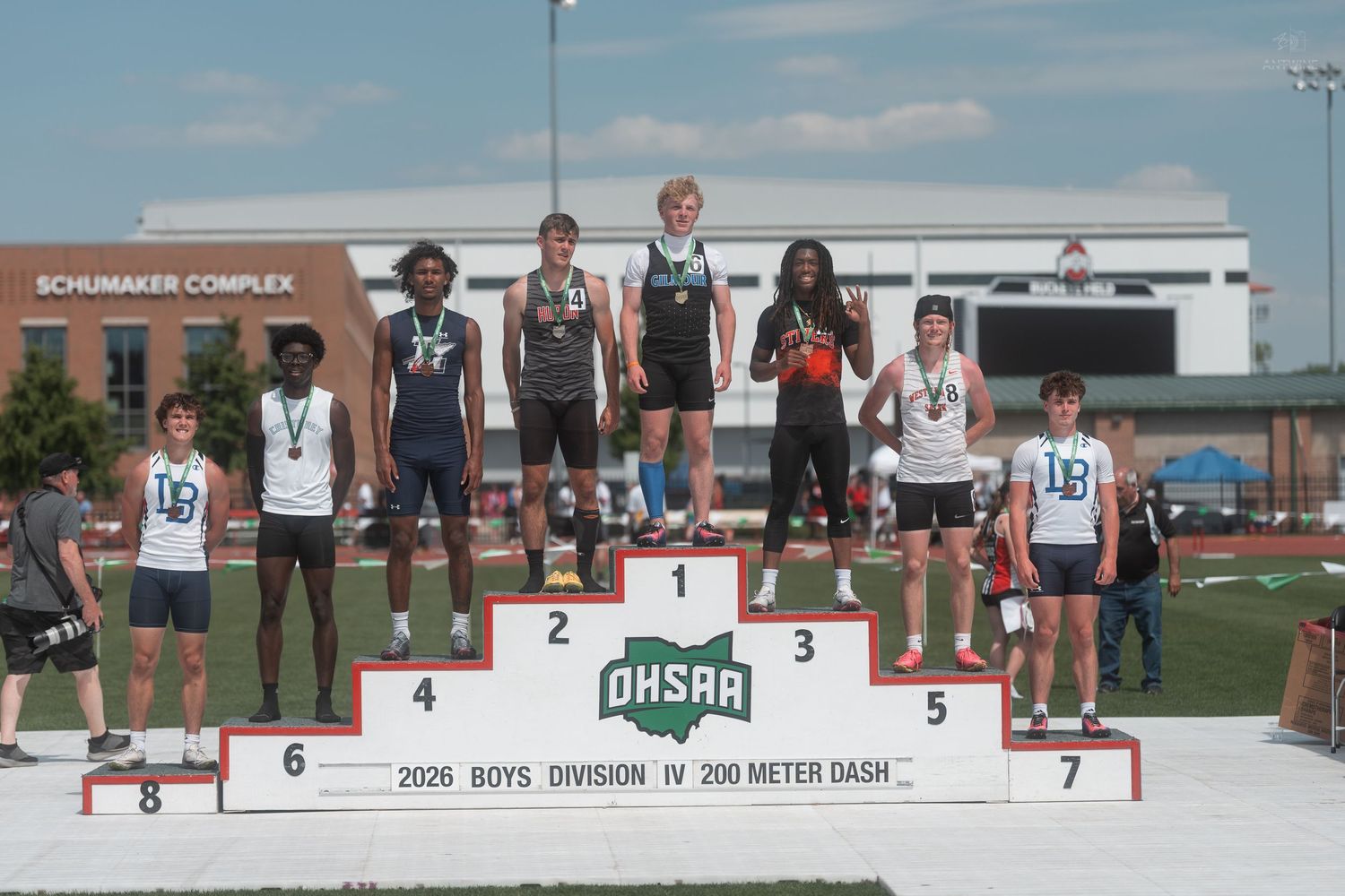 Seven young male athletes pose on the OHSAA Boys Division IV 200 Meter Dash awards podium.