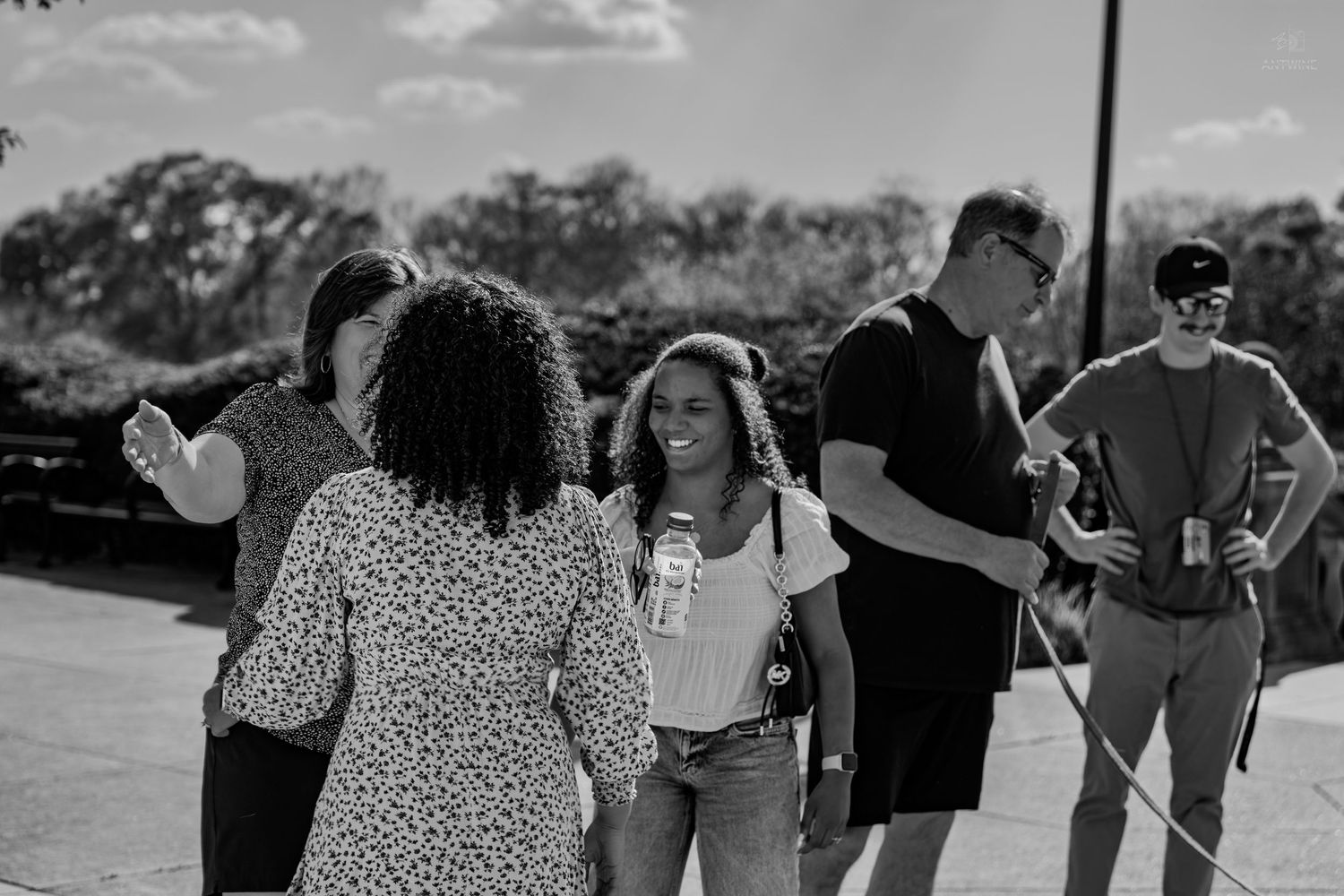 Black and white photo of a diverse group of people walking and talking outdoors.