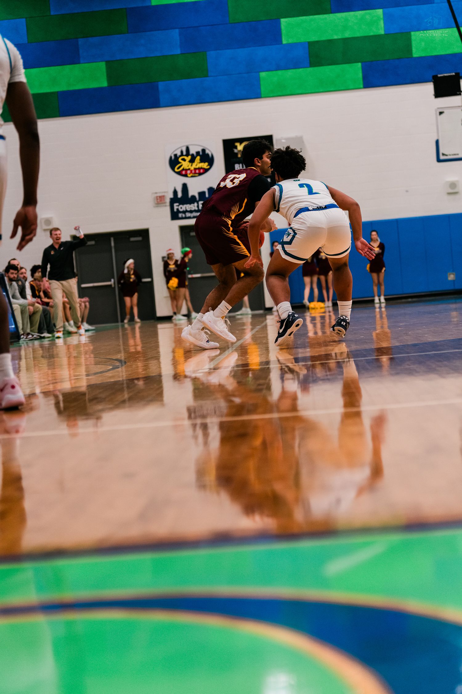 Two high school basketball players compete in a low-angle court shot during an intense game.
