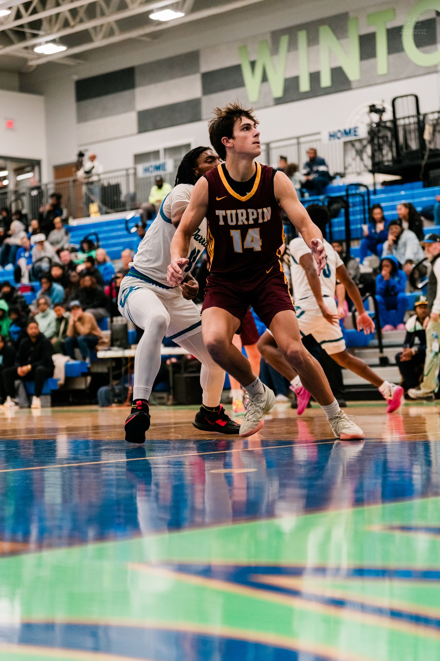Turpin High School basketball player number 14 boxes out opponent while tracking ball during game.
