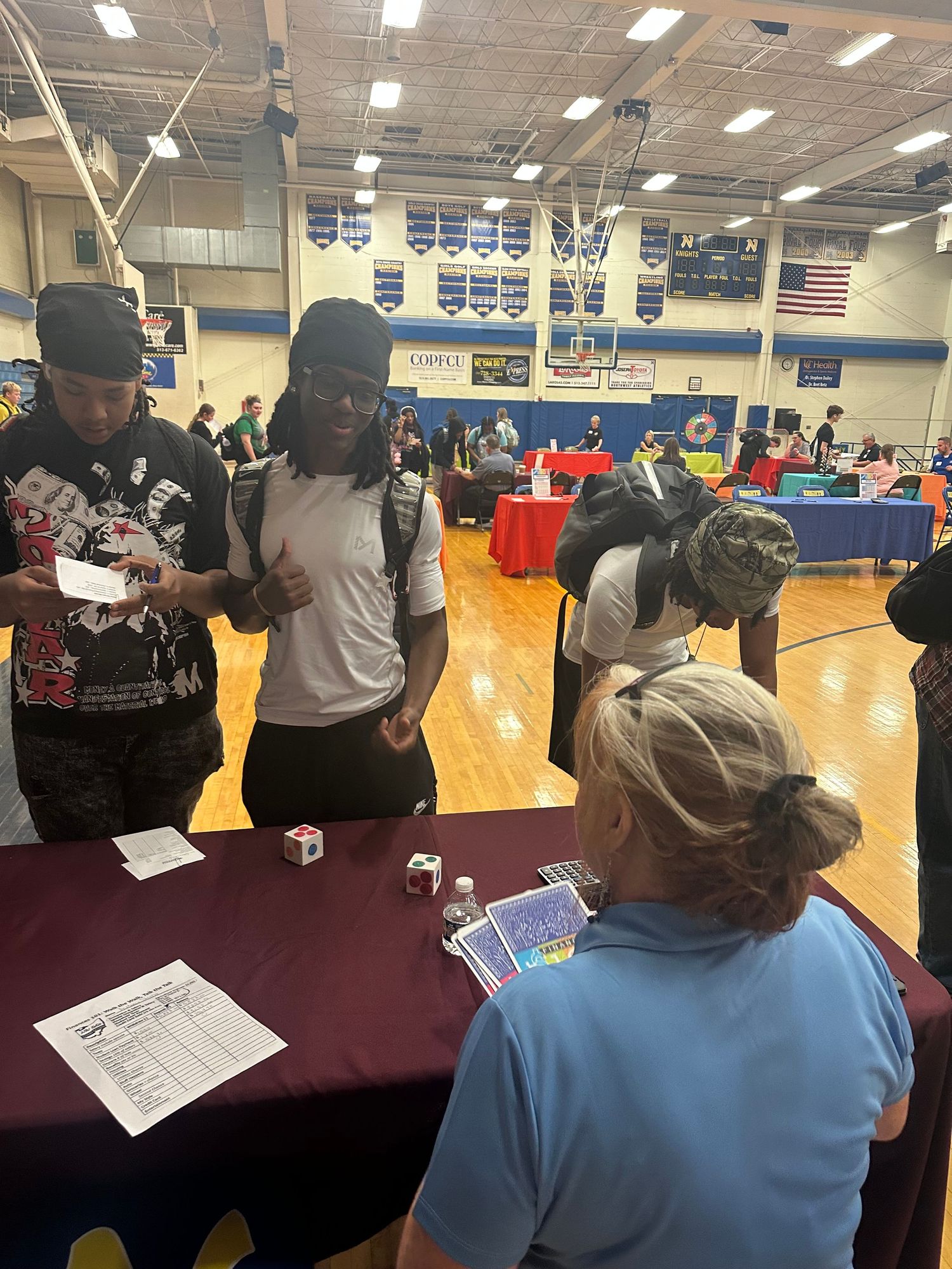 Students engage with a representative at a purple table during a busy school career fair event.