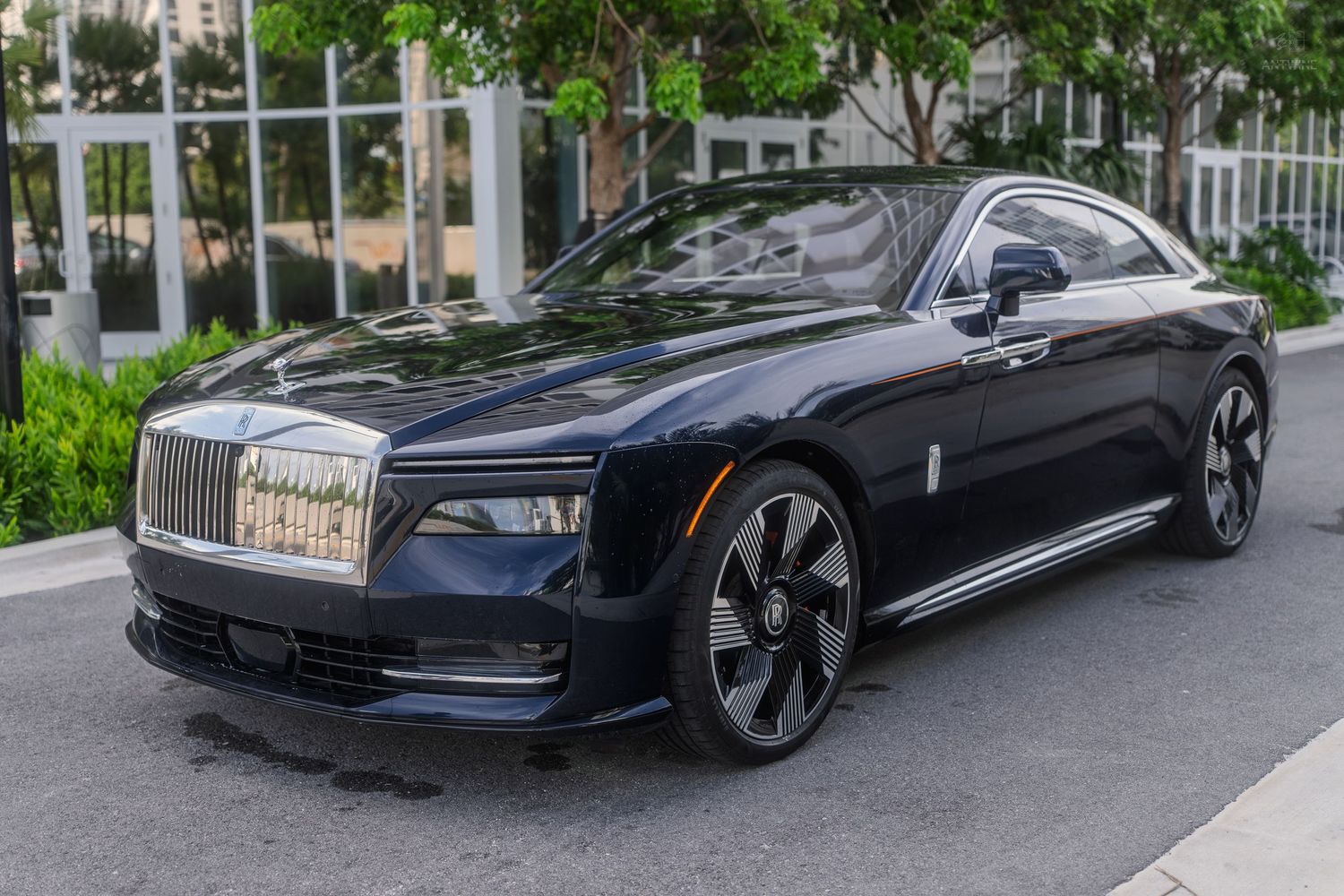 Luxury dark navy blue Rolls-Royce Spectre electric coupe parked outdoors in an upscale urban setting.