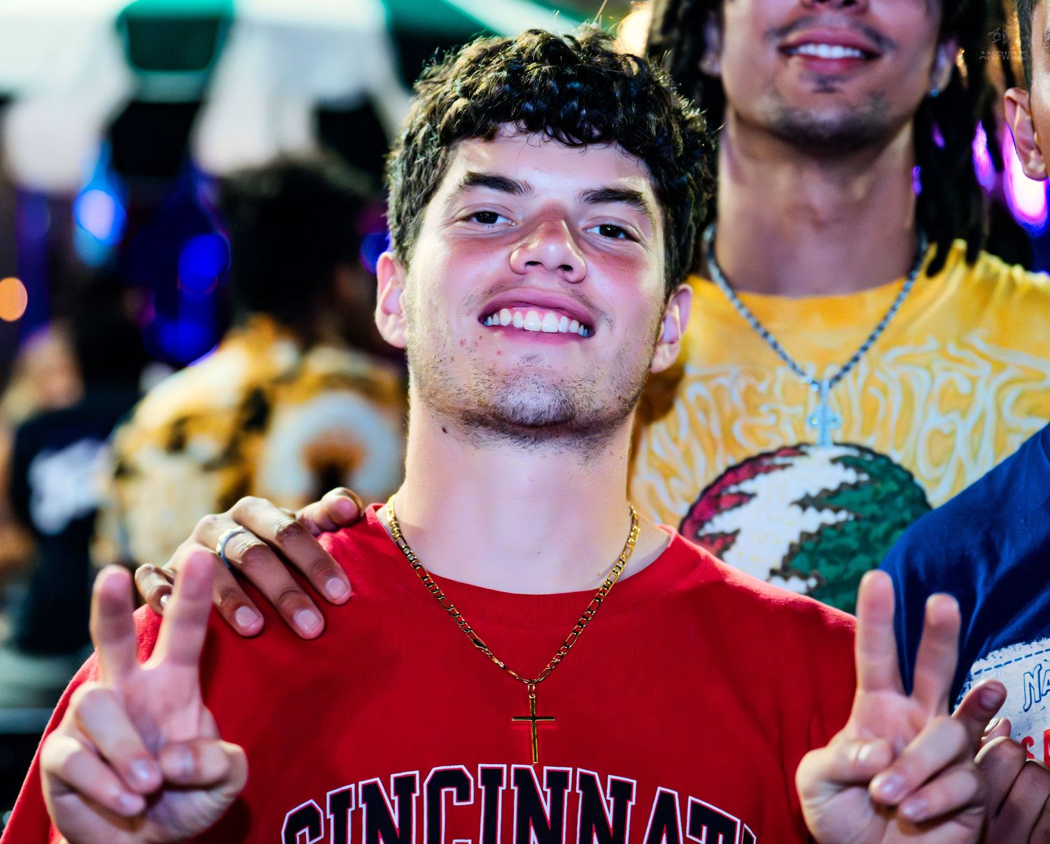Young man in Cincinnati shirt flashing peace signs at a festival.