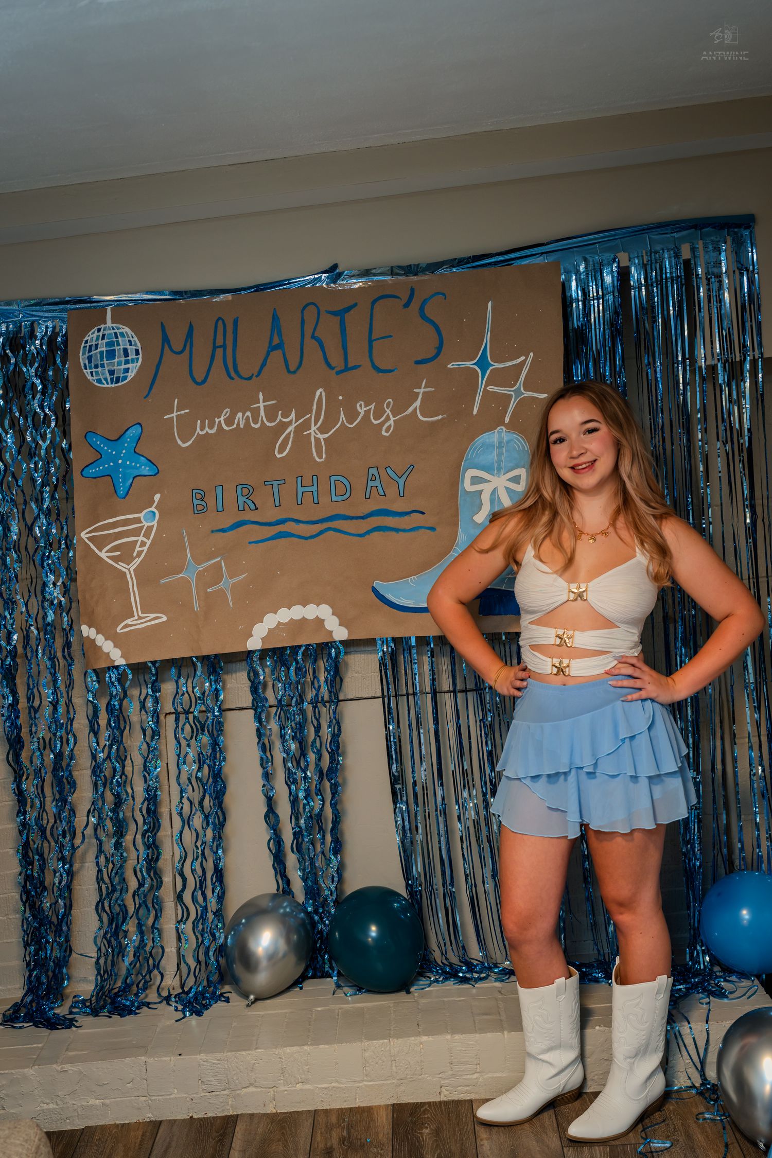 Woman with hands on hips posing confidently at Malarie's twentyfirst birthday party with blue decor.