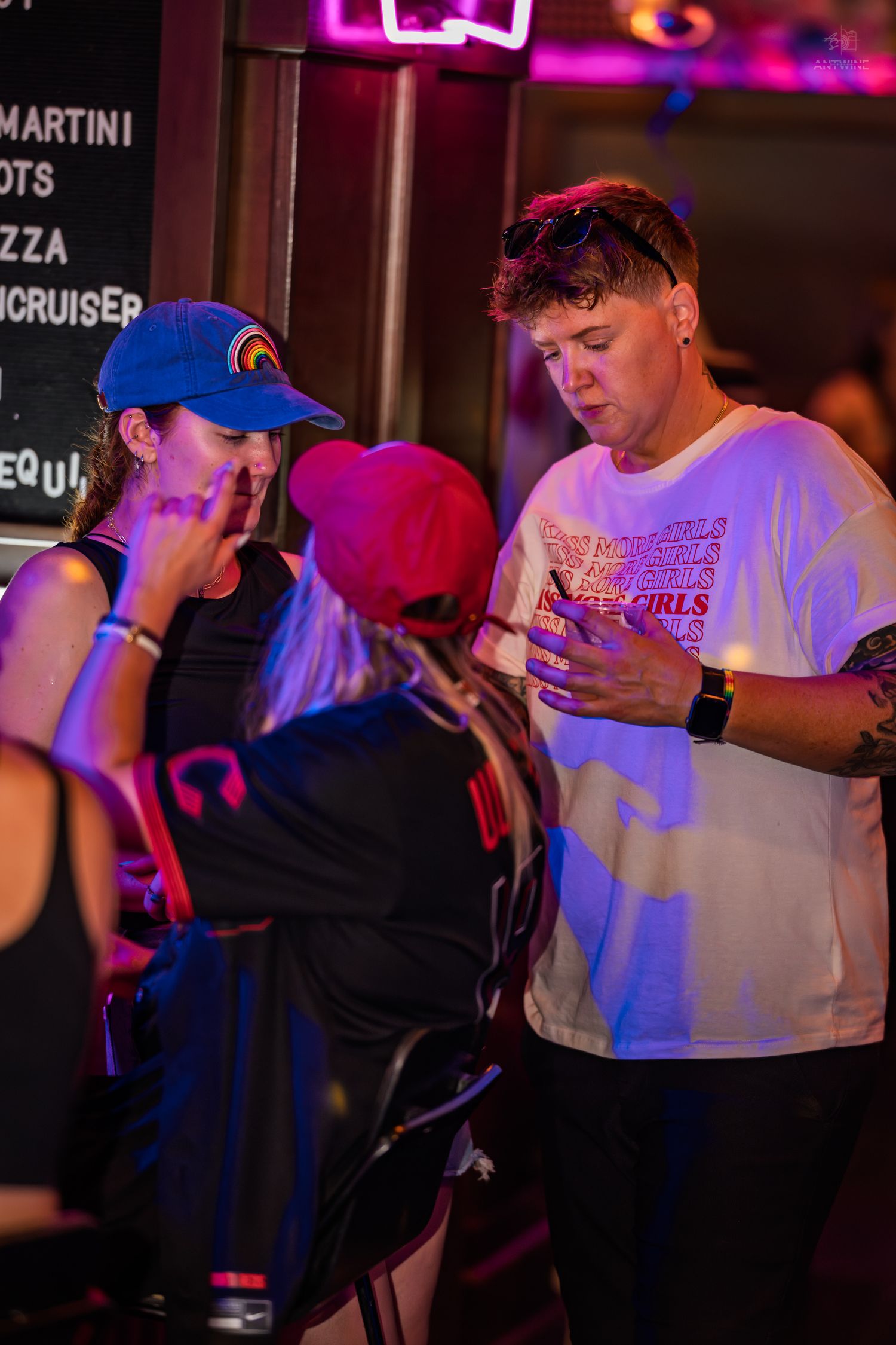 Group of young people interacting under neon lights inside a lively bar.