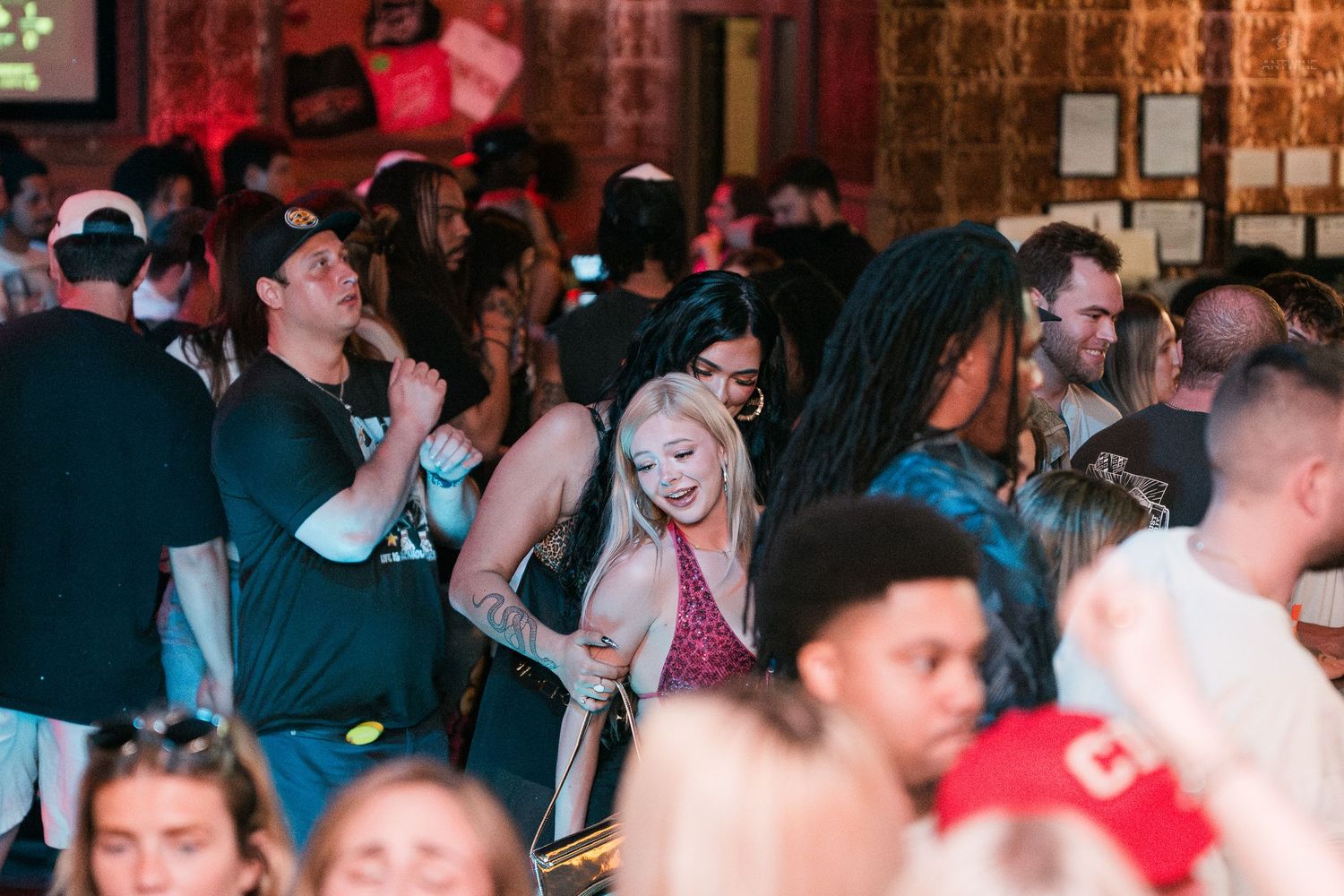 A crowd of young adults socializing and dancing at a lively indoor bar nightlife event.