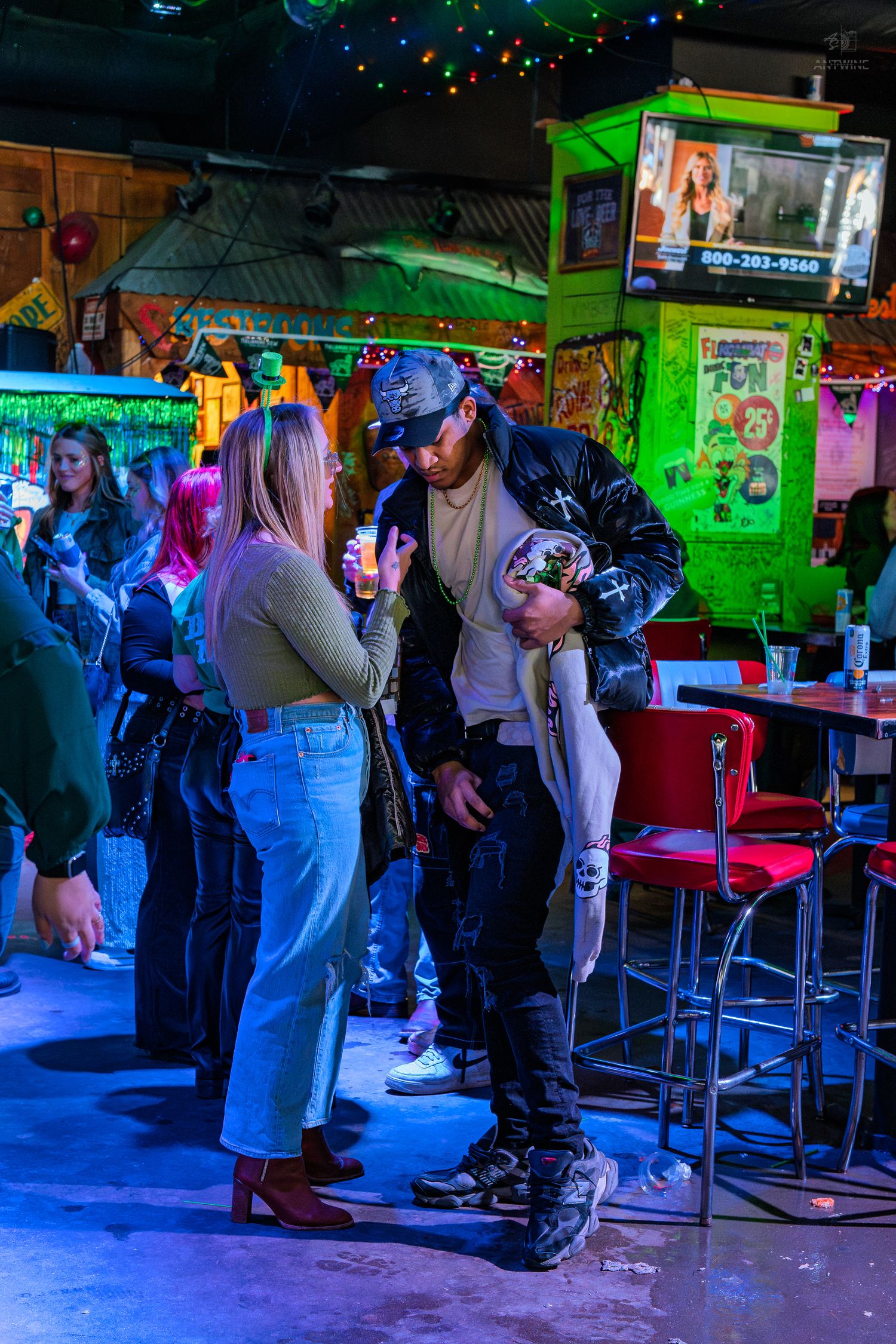 Couple dancing together in a colorful neon-lit bar with festive string lights.